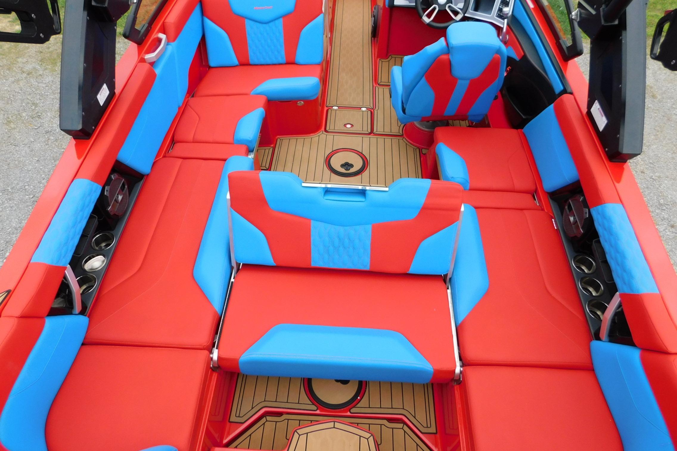 2022 MasterCraft NXT24 boat interior with vibrant red and blue seating and wood accents.
