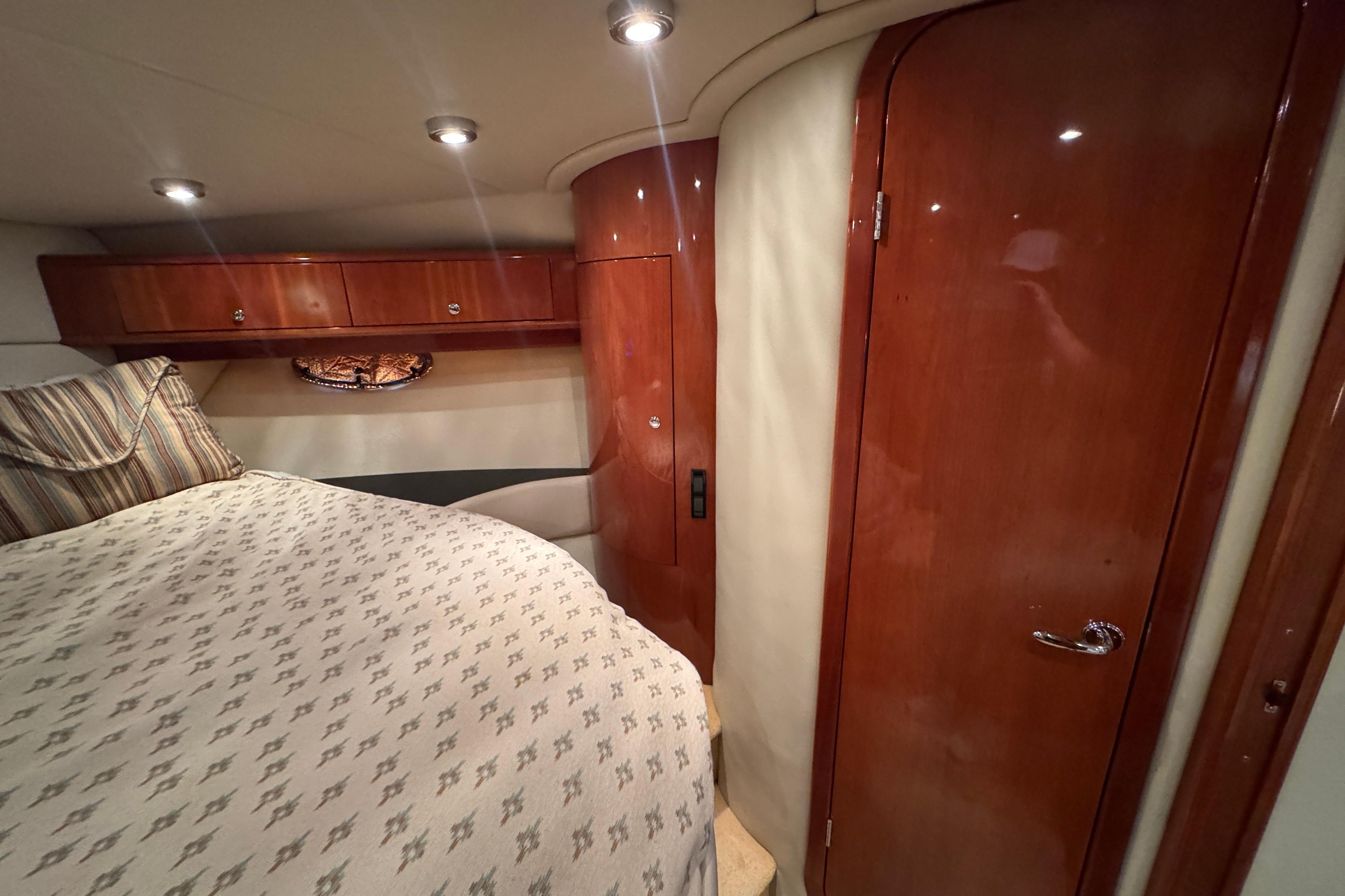 Luxurious cabin interior of 2005 Regal Commodore 4260 yacht with wood finish and cozy bedding.