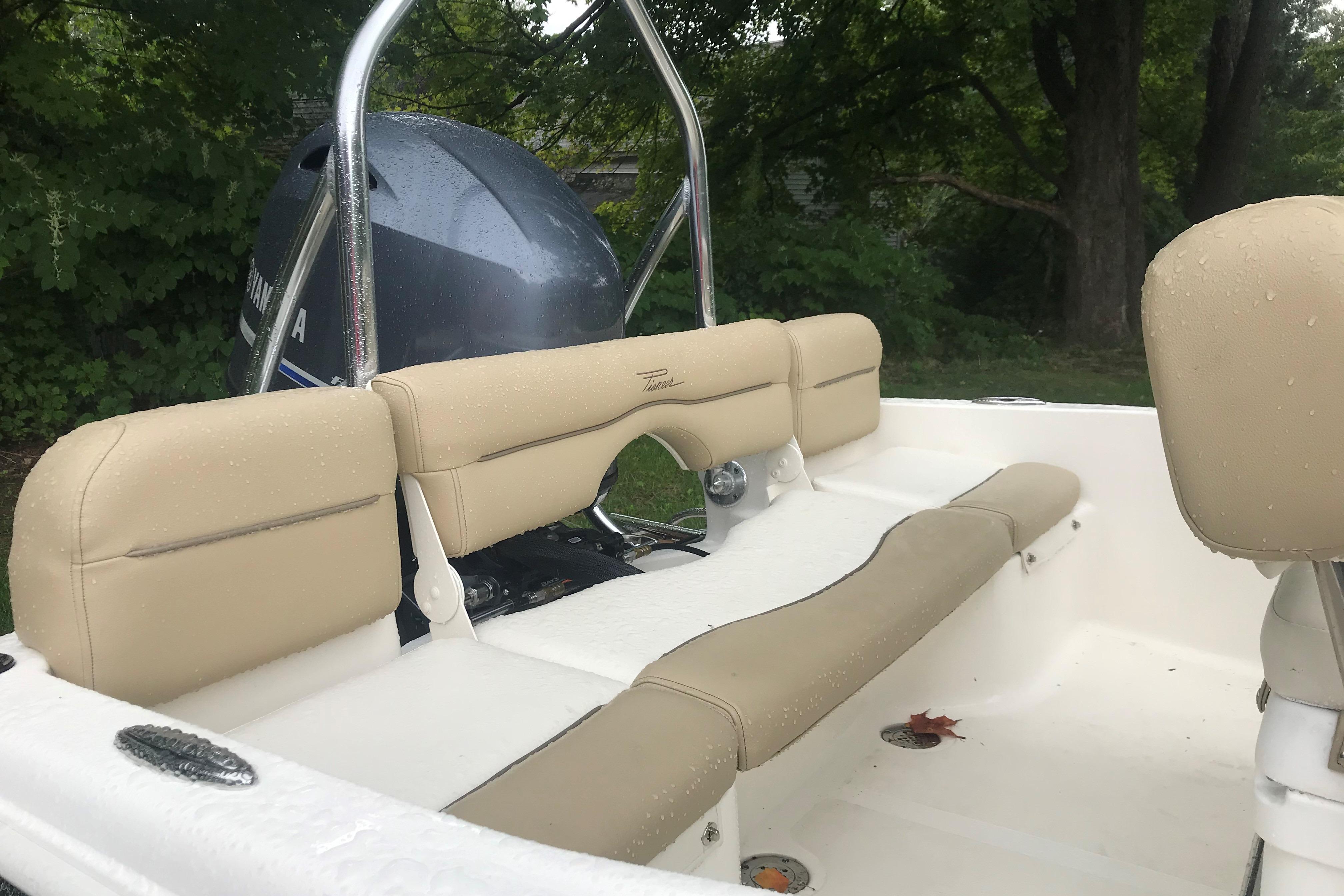 2026 Pioneer 180 Islander boat interior with beige seating and Yamaha engine, outdoors.