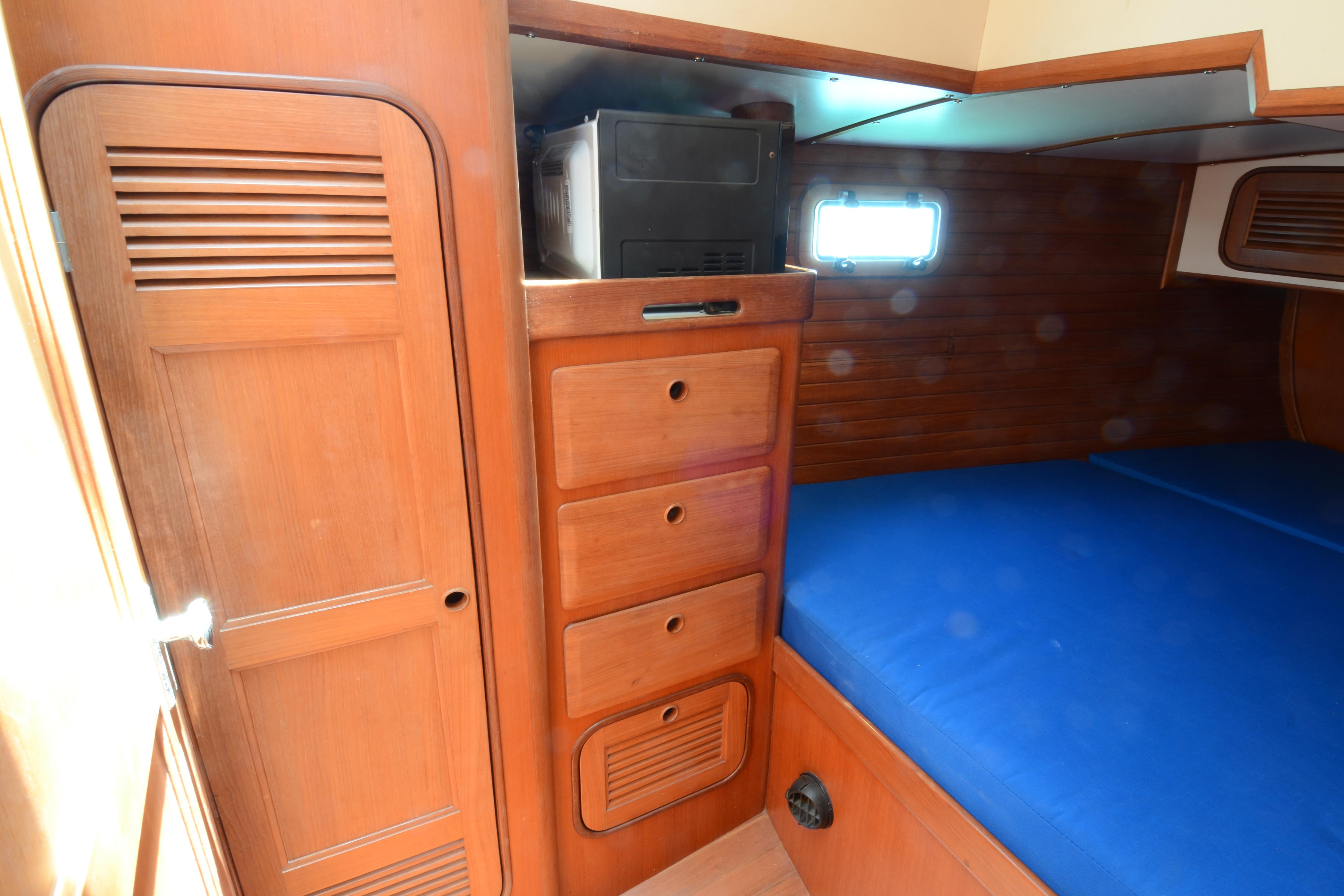 Interior of 1987 Norseman 400 yacht with wooden cabinetry and blue bedding.