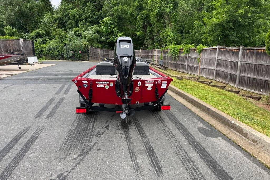 2022 Tracker Pro 170 boat on trailer, parked on asphalt near wooden fence.