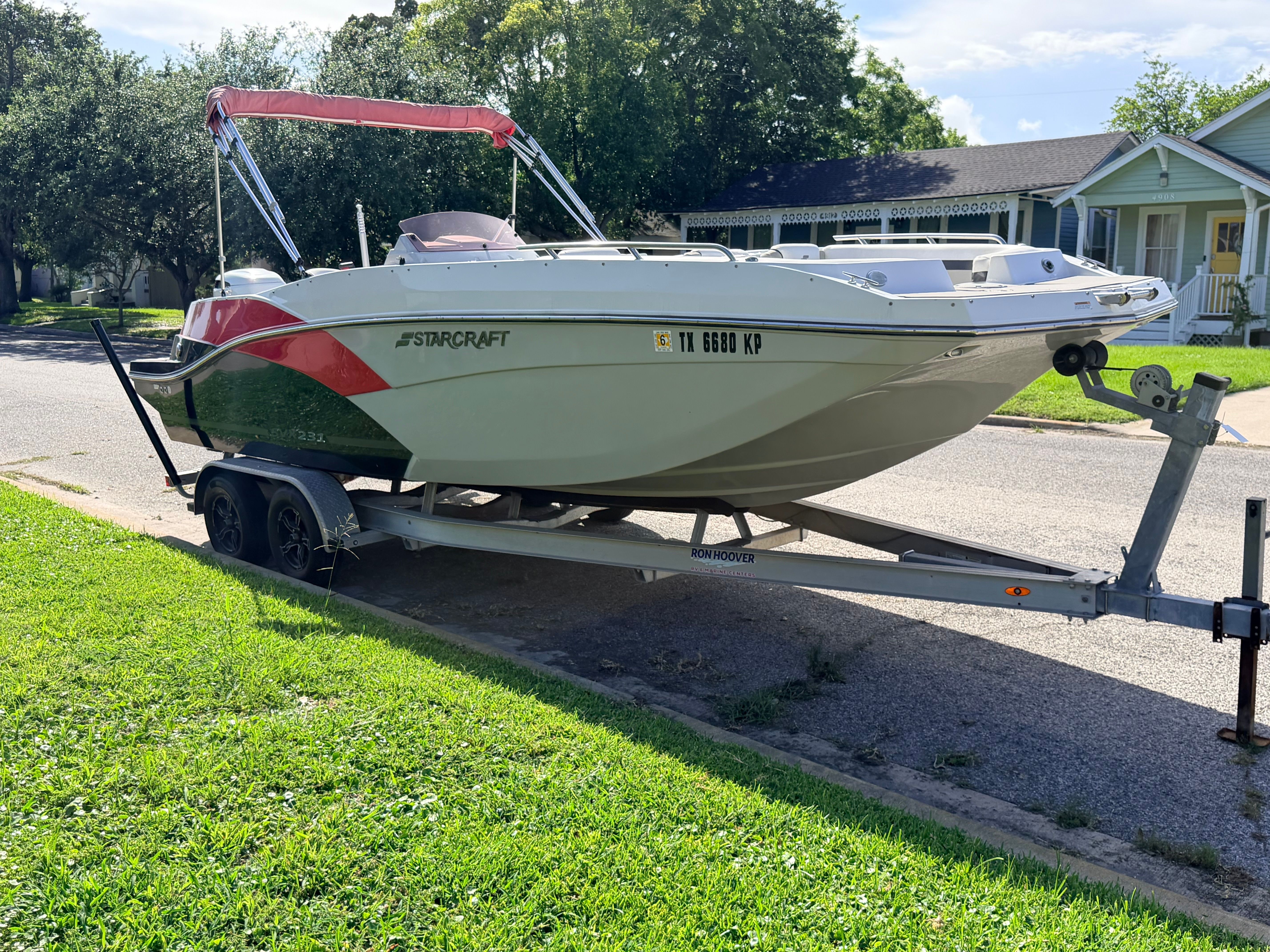 A 2022 Starcraft SVX 231 boat is on a trailer in a residential street.