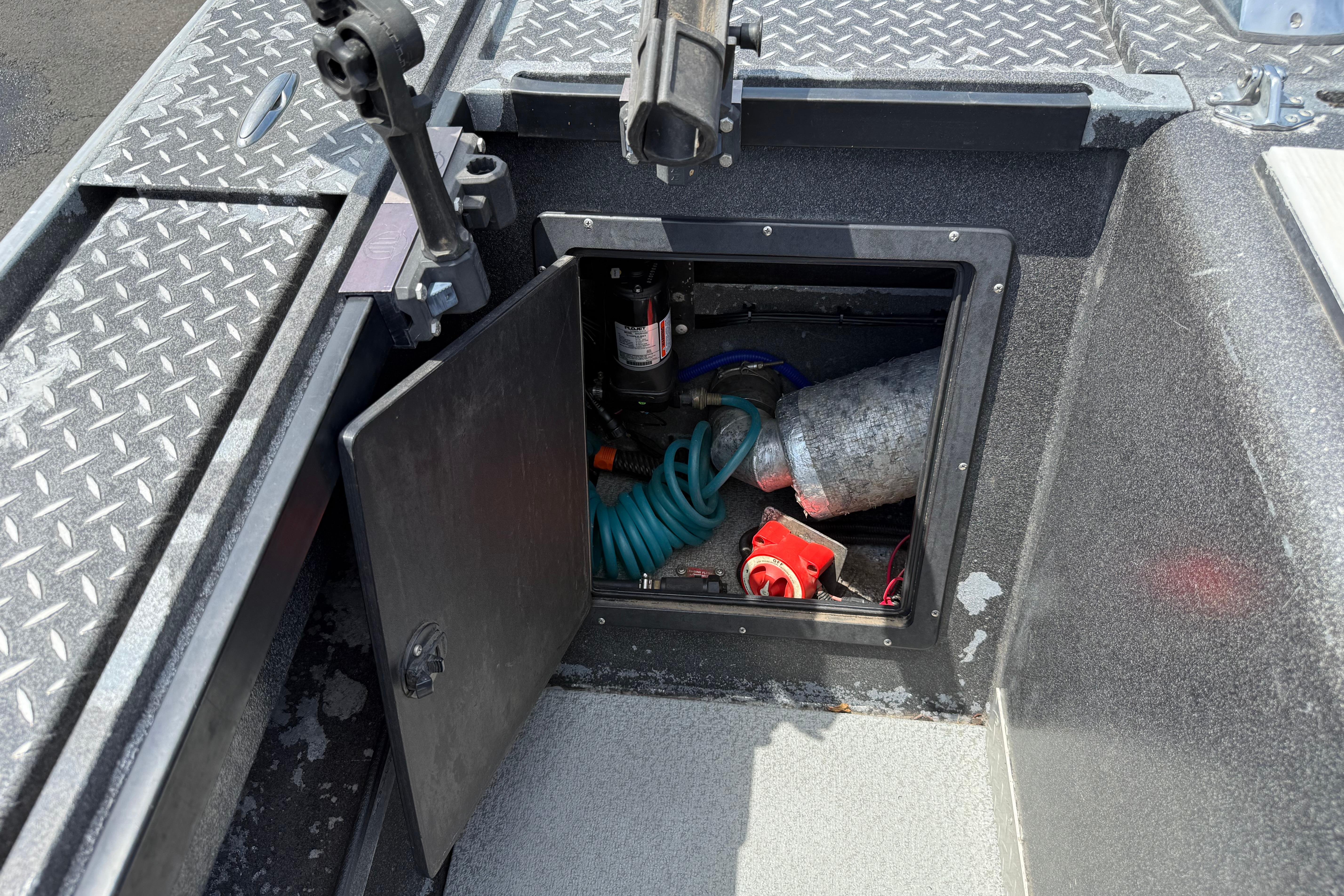 Open storage compartment on a 2005 Willie Raptor 21' boat with various equipment inside.