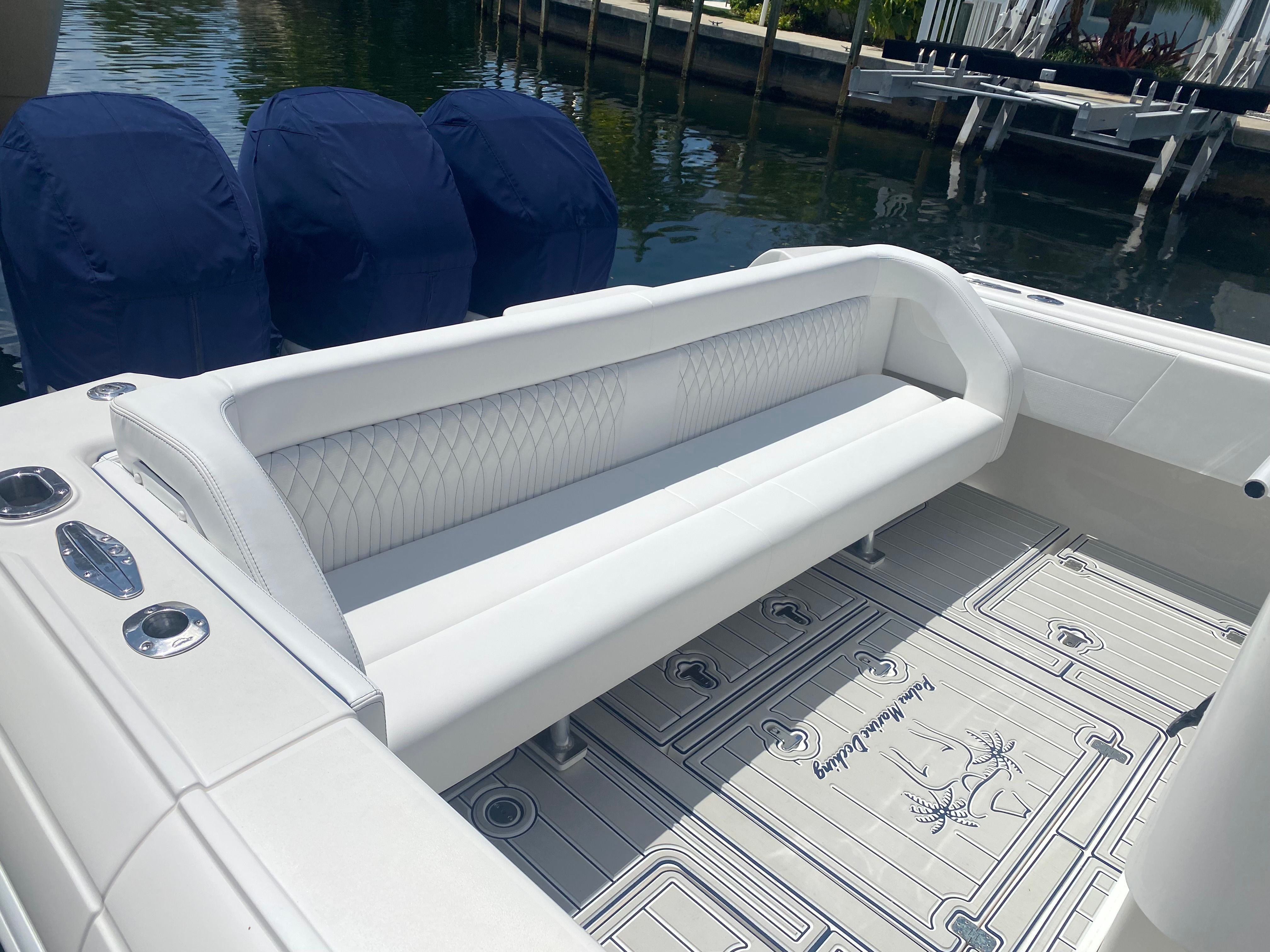 A white bench seat on a boat with textured flooring, near a calm waterway.