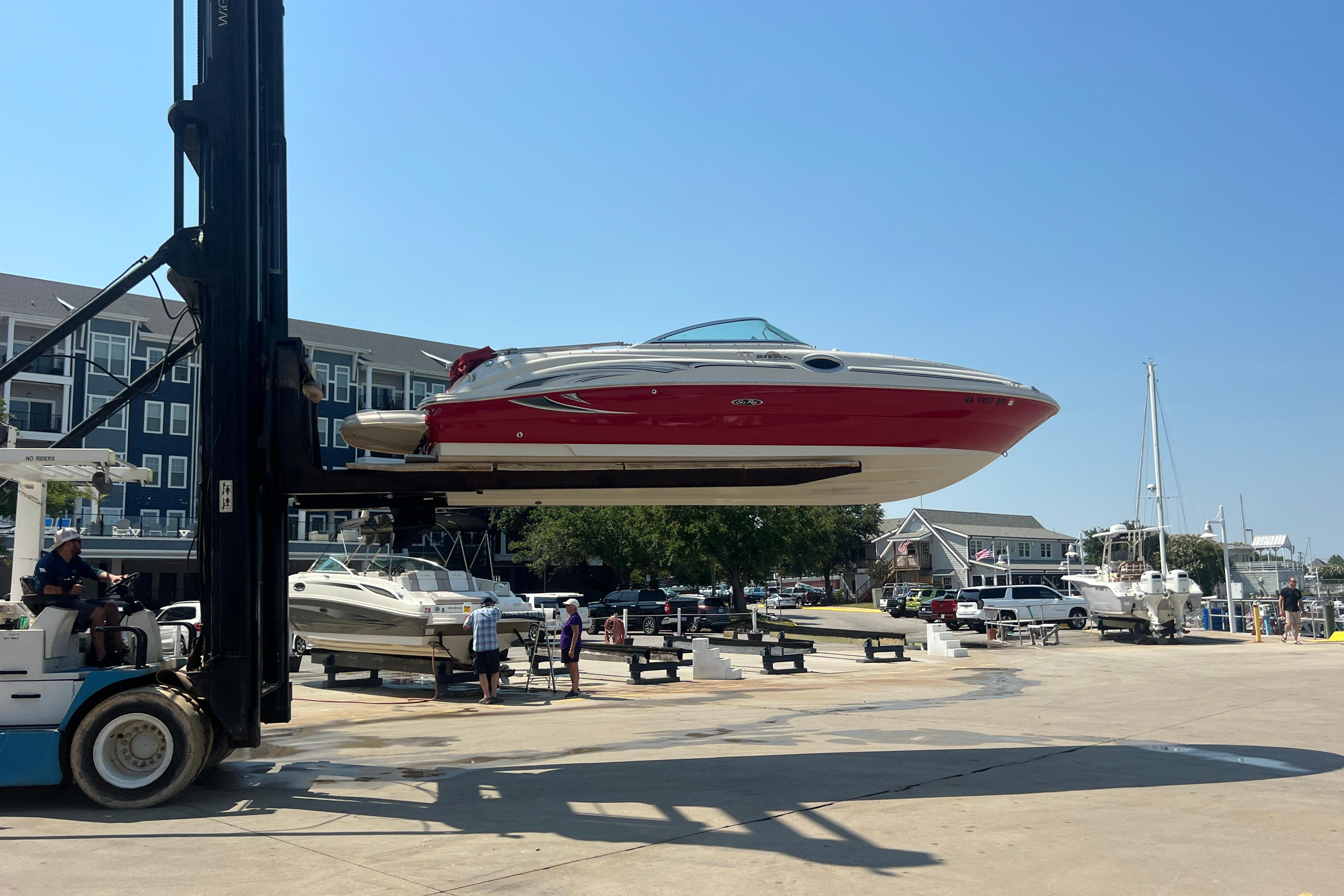 2005 Sea Ray 240 Sundeck boat lifted by forklift at marina.