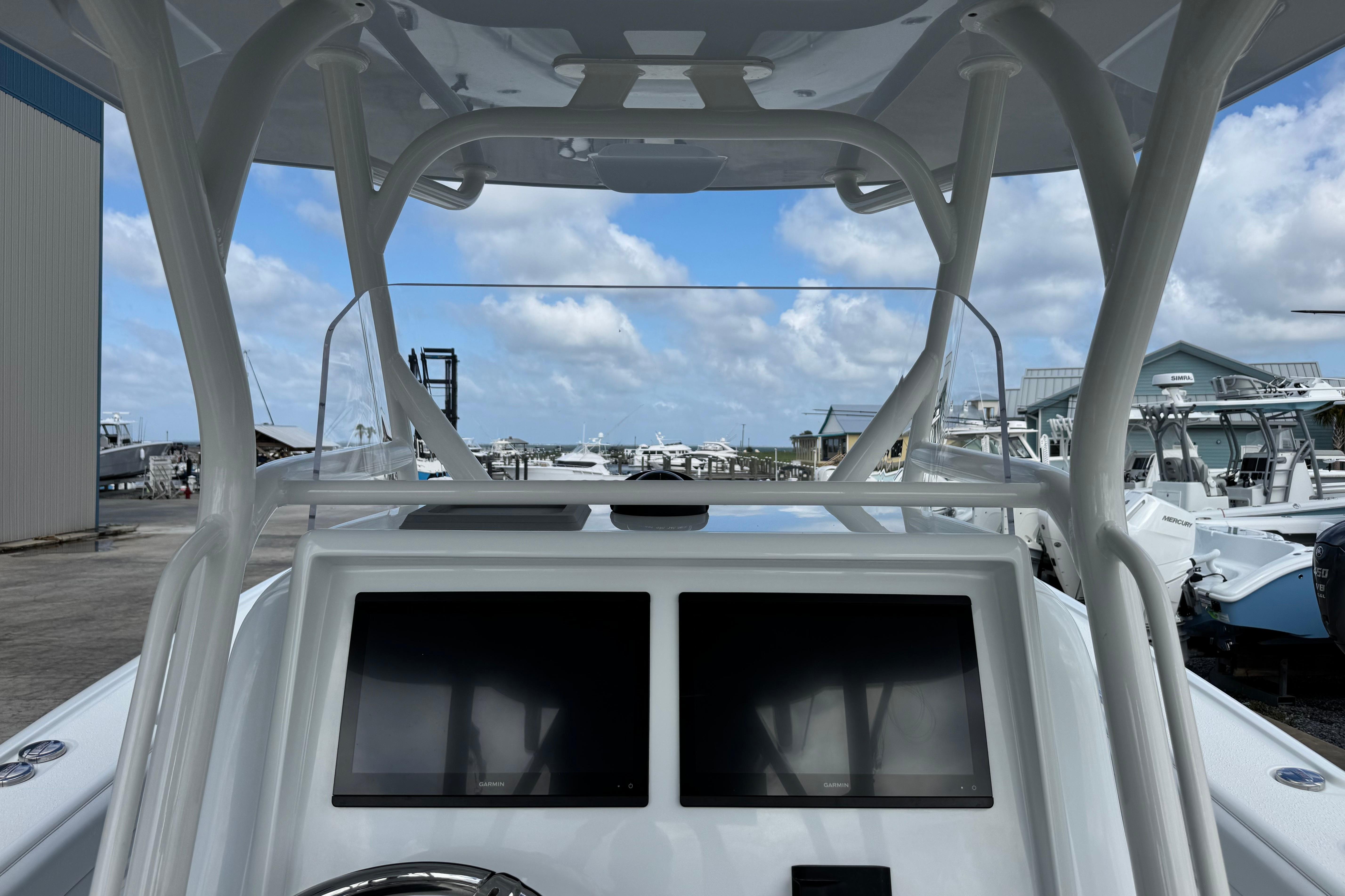 2022 Yellowfin 32 Offshore boat dashboard with dual screens, marina background.