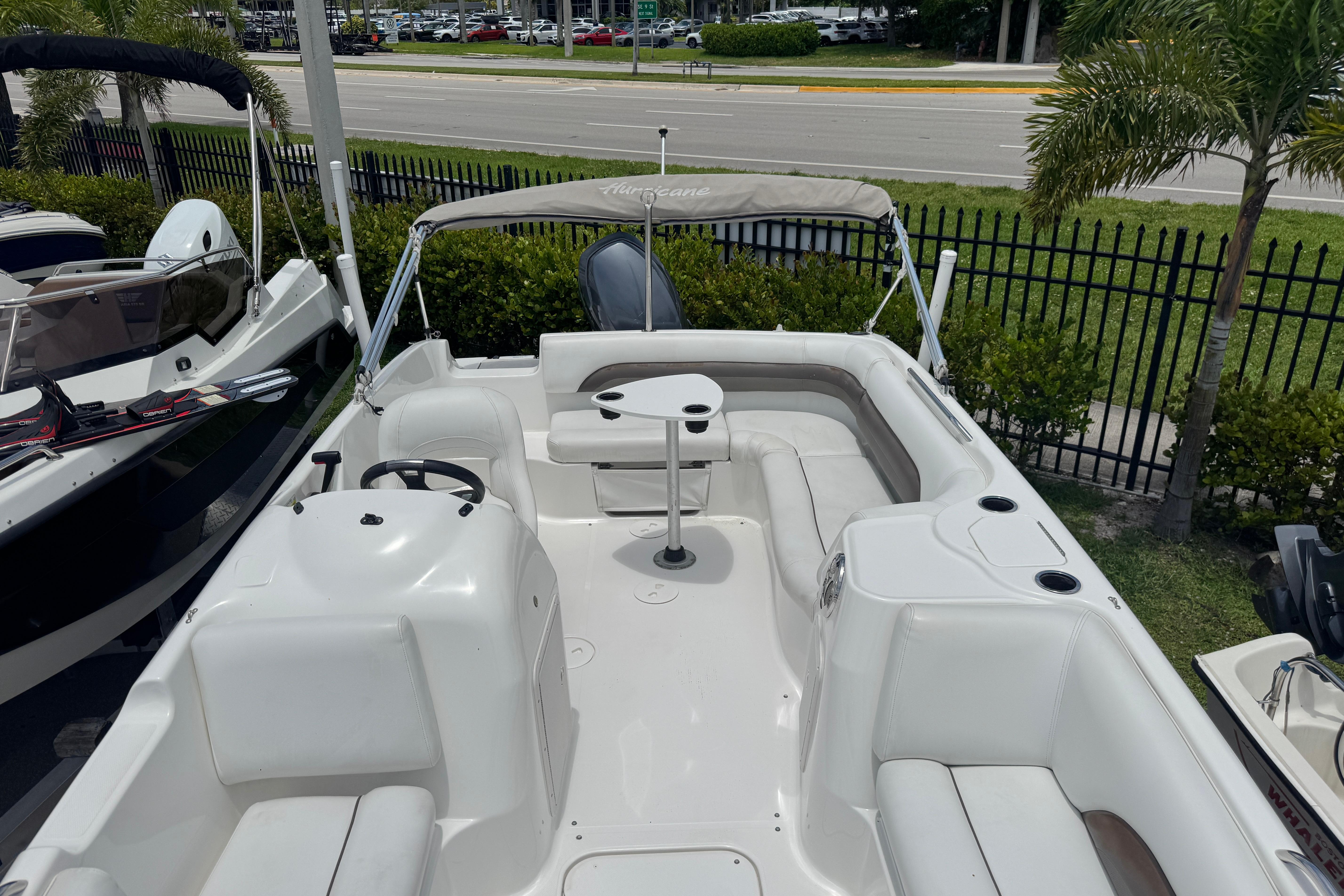 2013 Hurricane SunDeck Sport 188 OB boat with seating and table, parked outdoors.