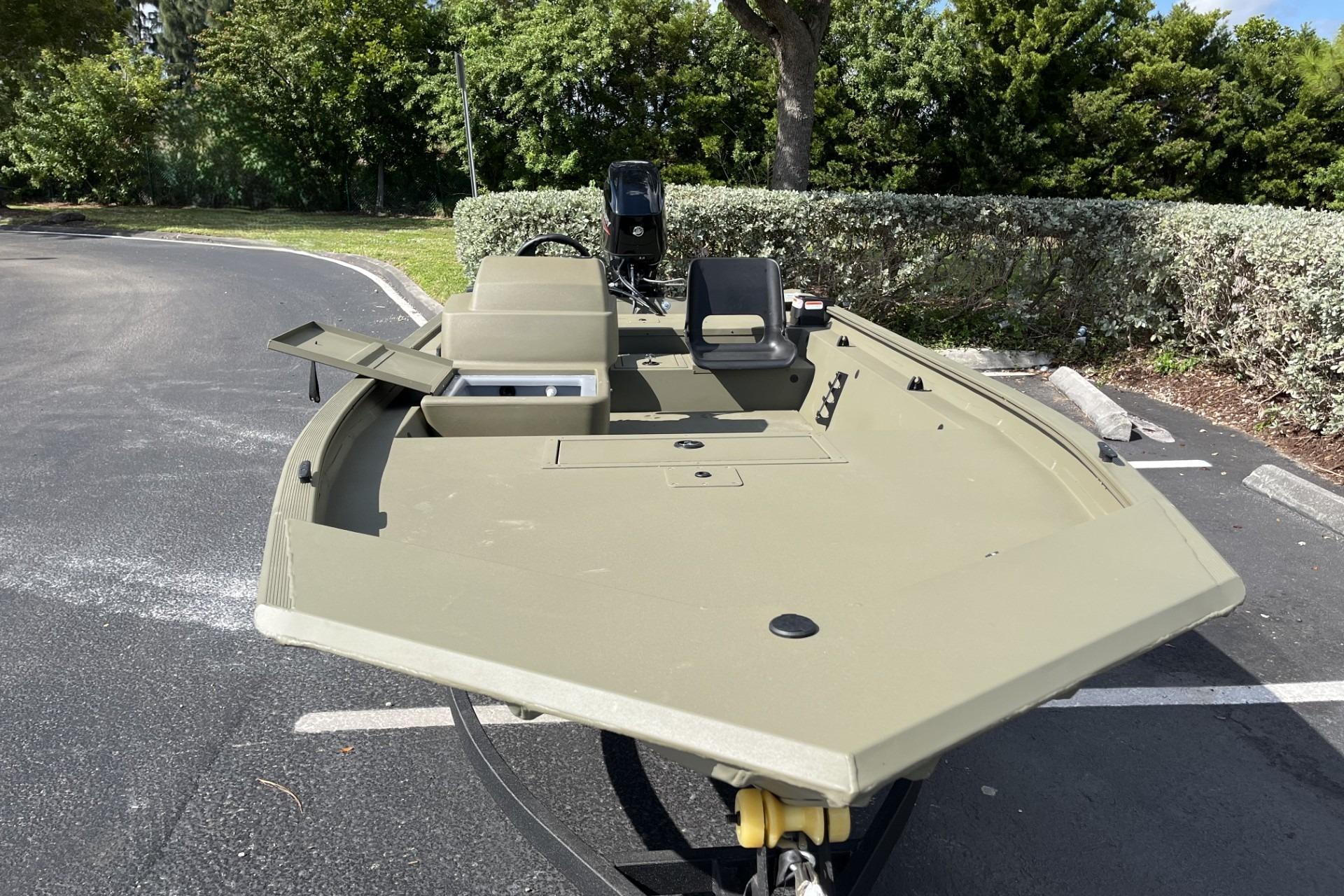 2026 Tracker Grizzly 1754 SC boat parked, showcasing open storage compartments and seating.