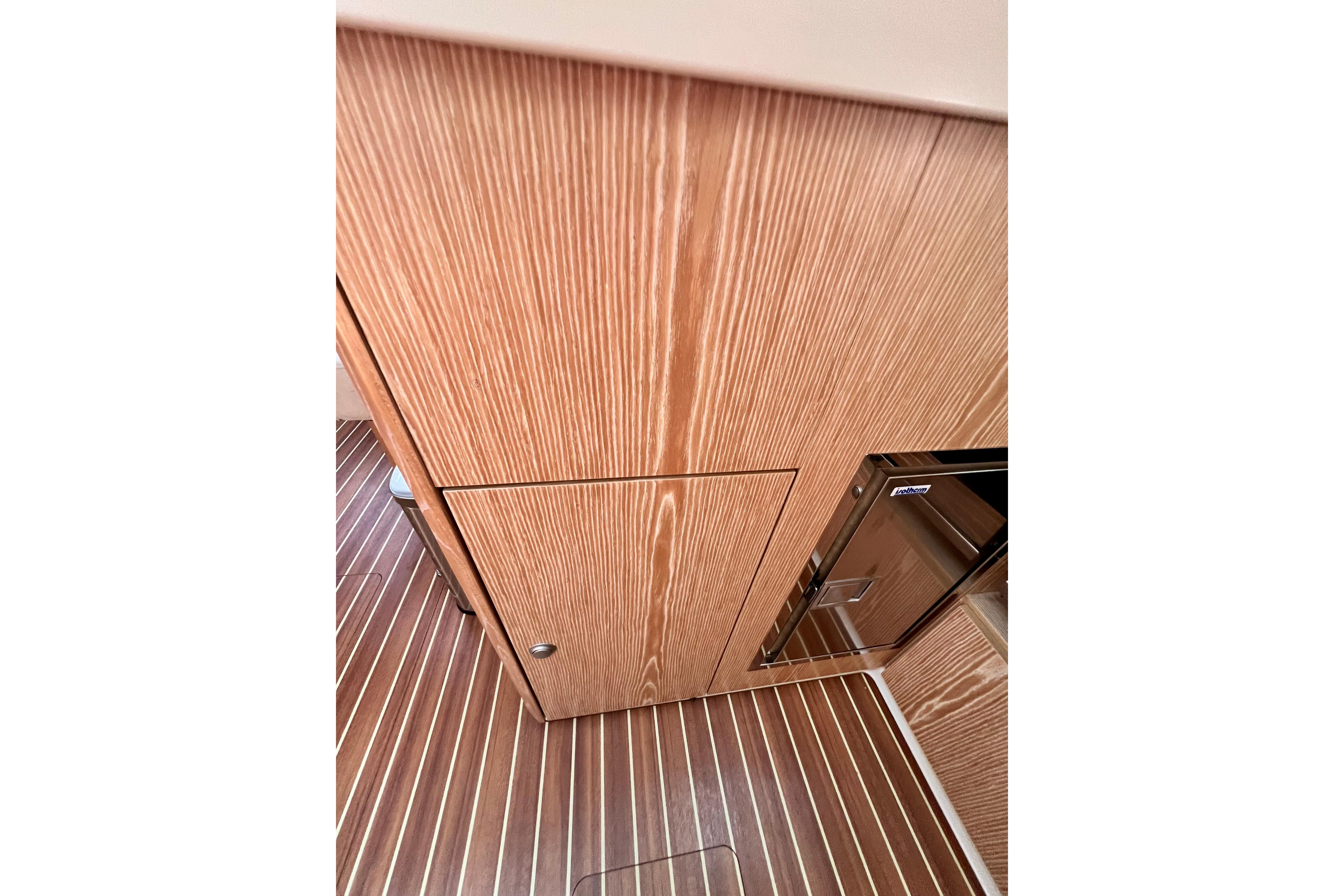 Wooden interior of 2016 Hanse 455 yacht, featuring sleek cabinetry and striped flooring.