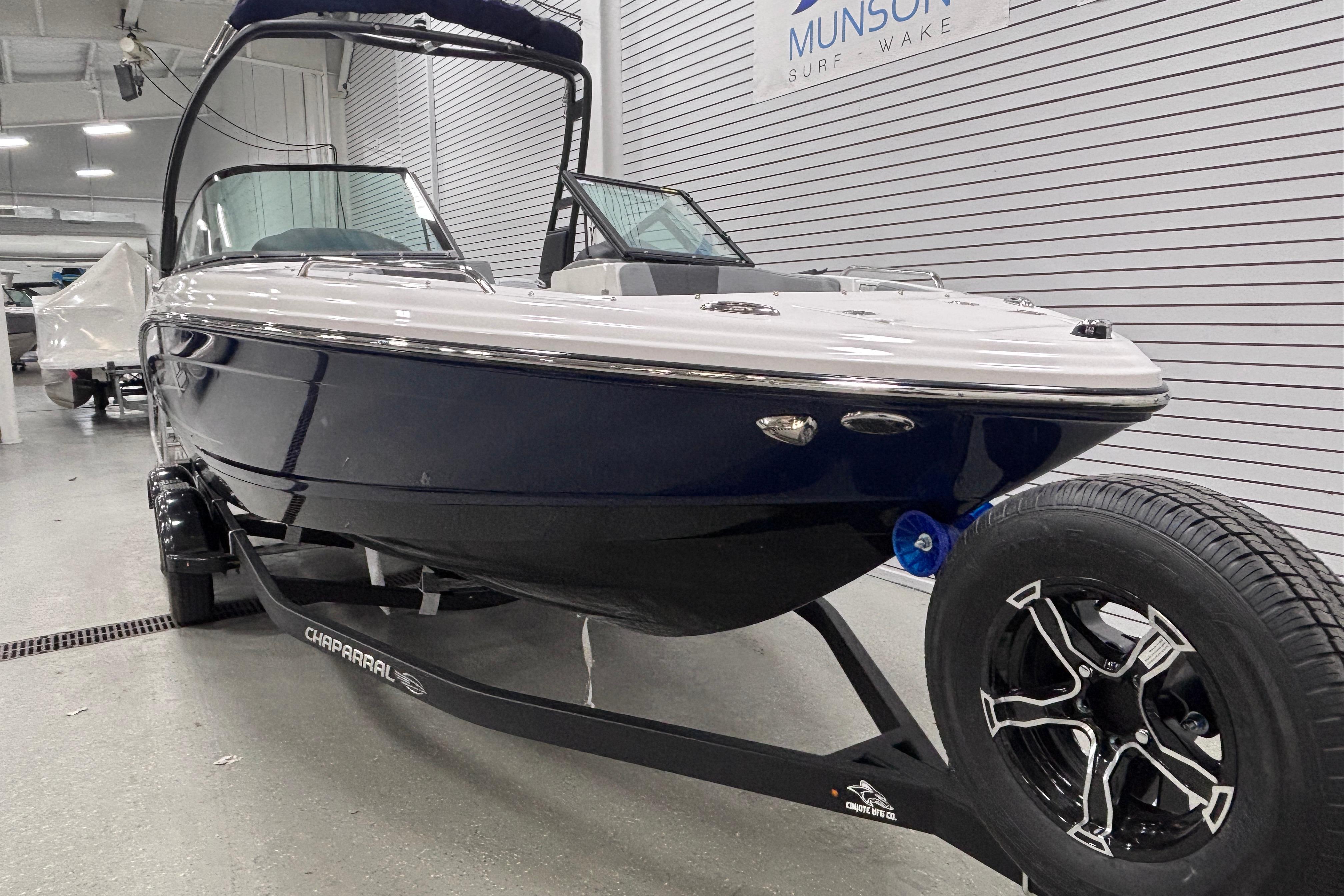 2026 Chaparral 23 SSi boat on trailer in showroom, sleek design, black and white exterior.