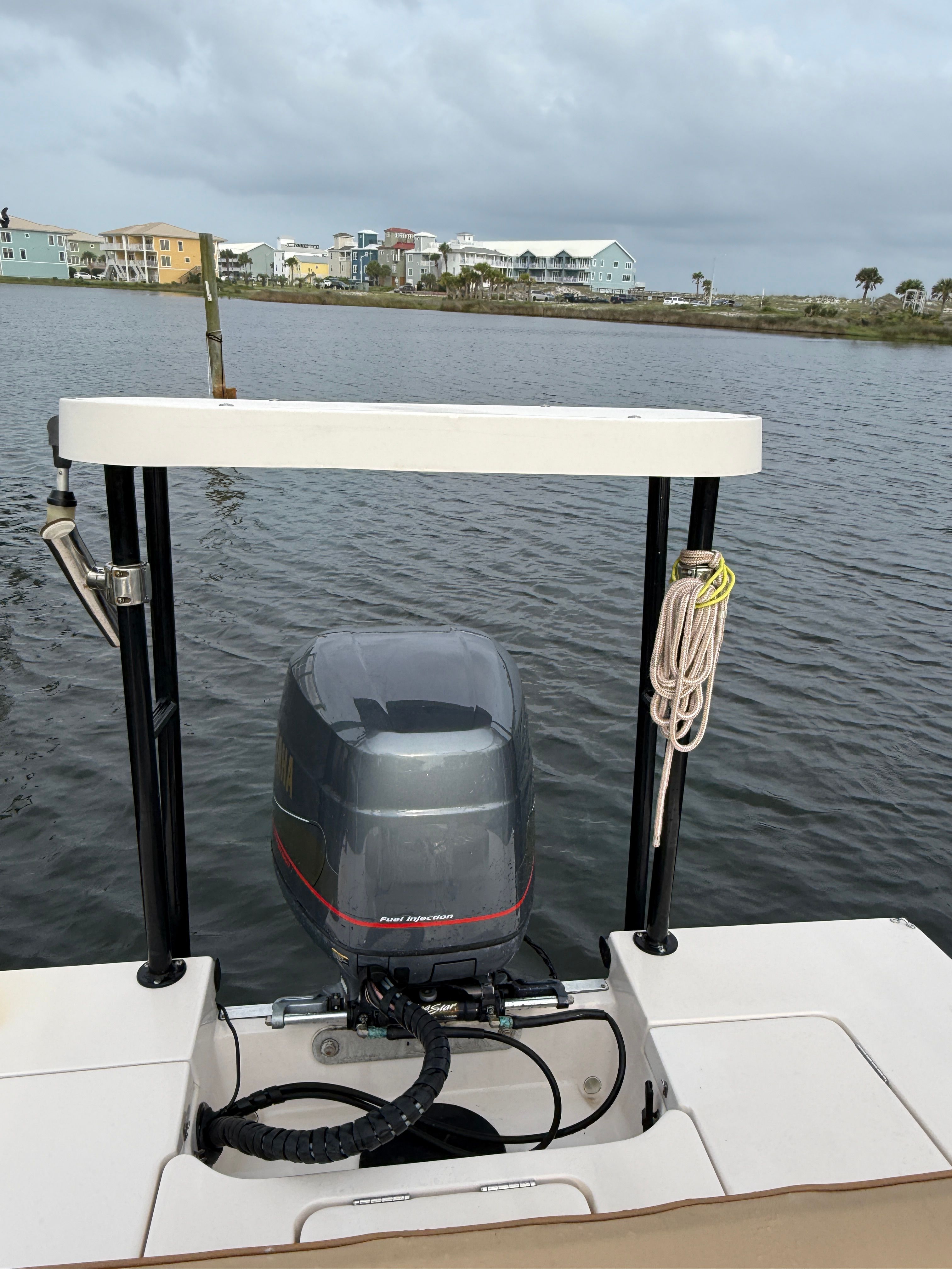 A 2003 Maverick 18 boat with an outboard motor on calm water, with a coastal backdrop.