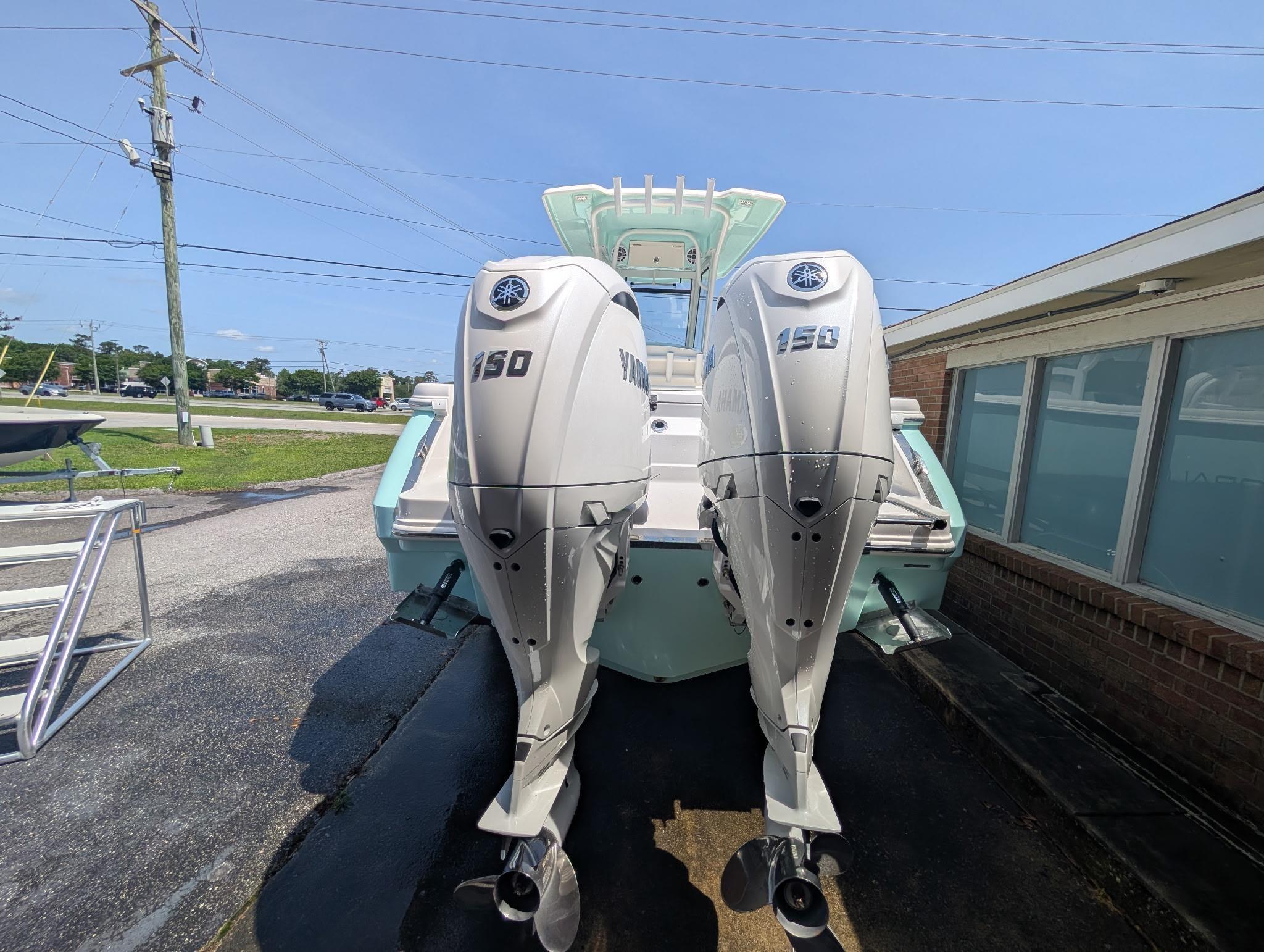 2025 Robalo R250 Center Console with dual Yamaha 150 engines, parked outdoors.