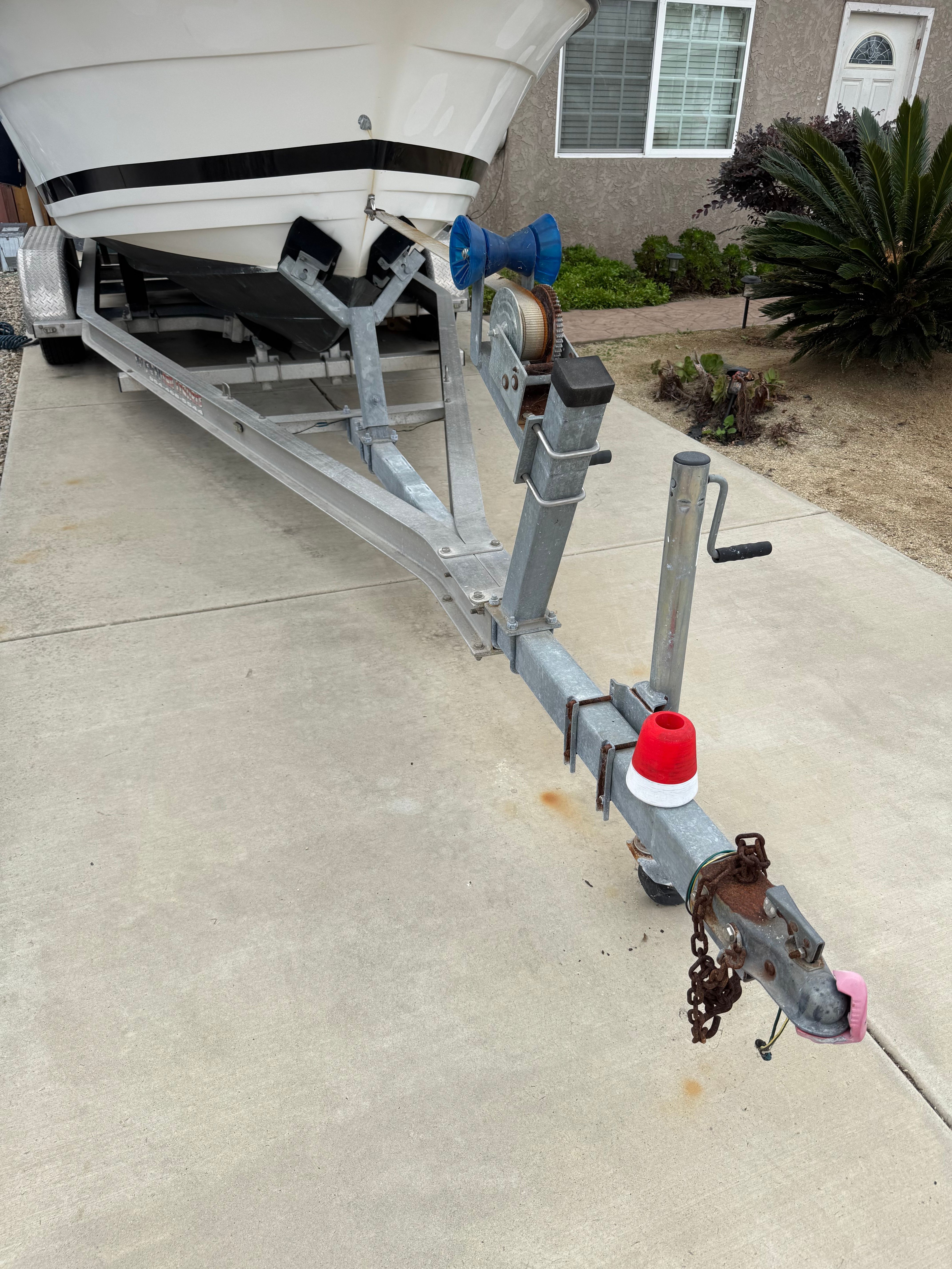 A 1999 Cobia Walkaround boat is on a trailer in a driveway.