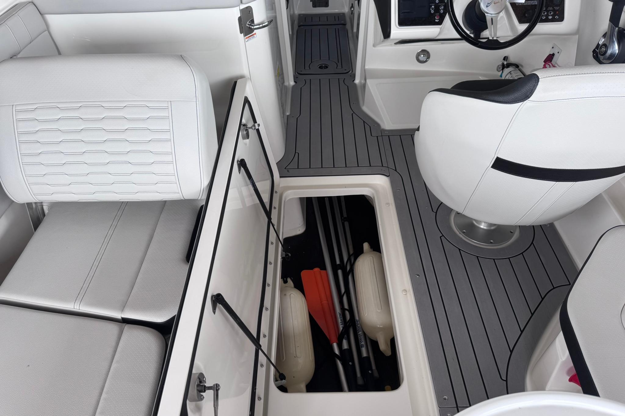 Interior of 2021 Sea Ray SPX 230 boat with white seating and storage compartment.