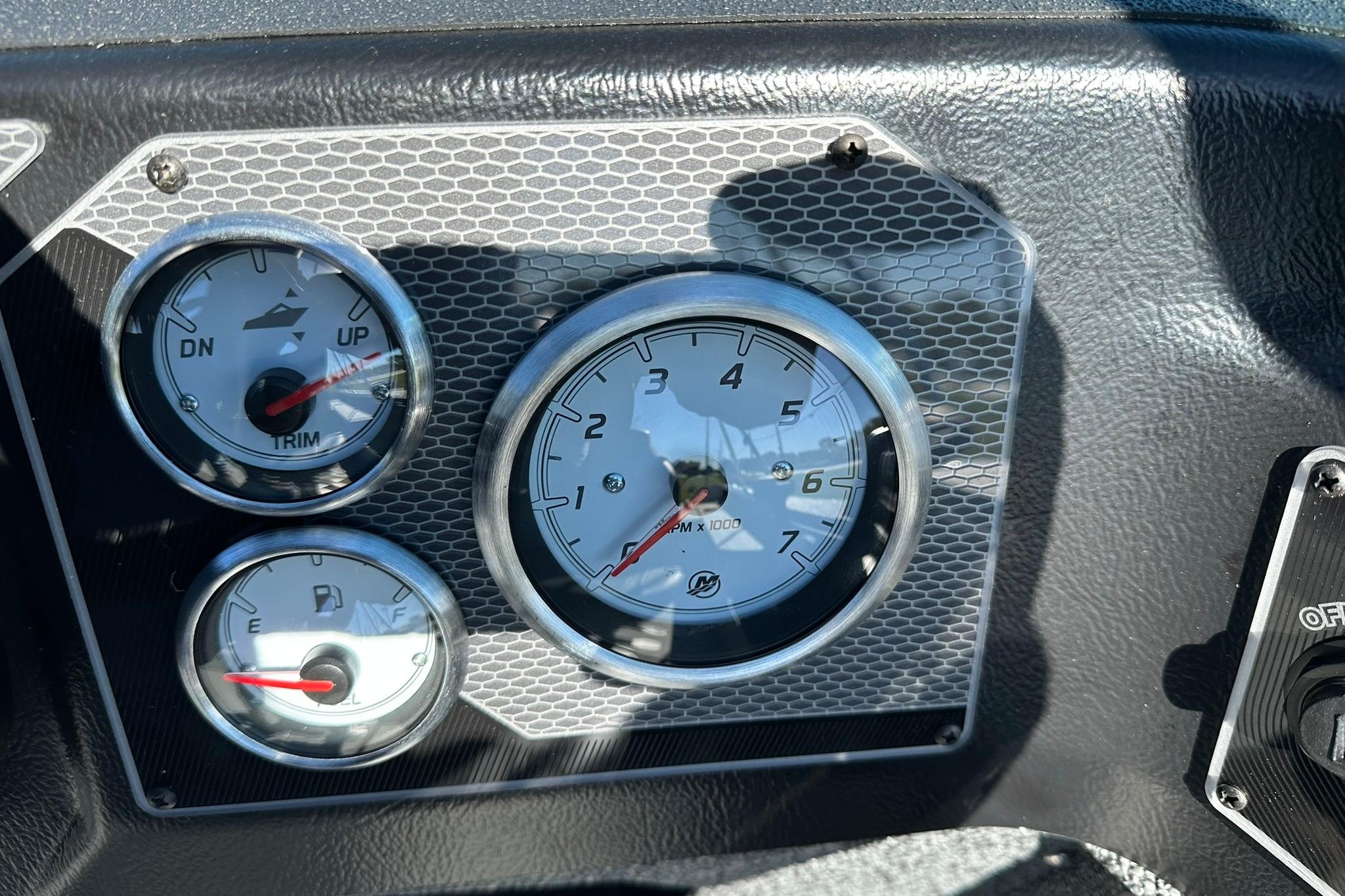 Dashboard gauges of 2026 Lund 1875 Impact XS Sport boat, showing trim, RPM, and fuel levels.