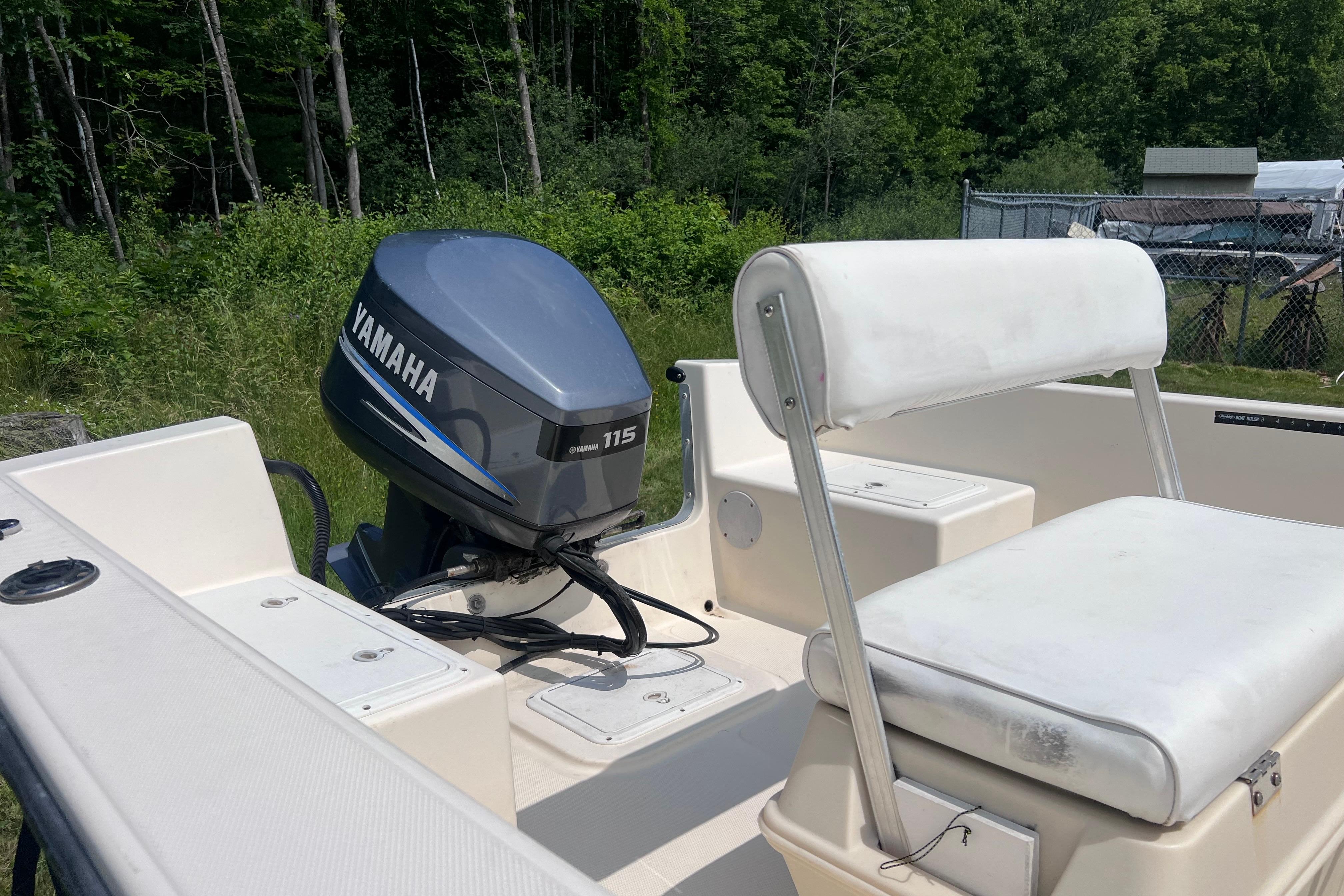 2003 May-Craft 1820CC boat with Yamaha 115 outboard motor, white seating, and lush green background.