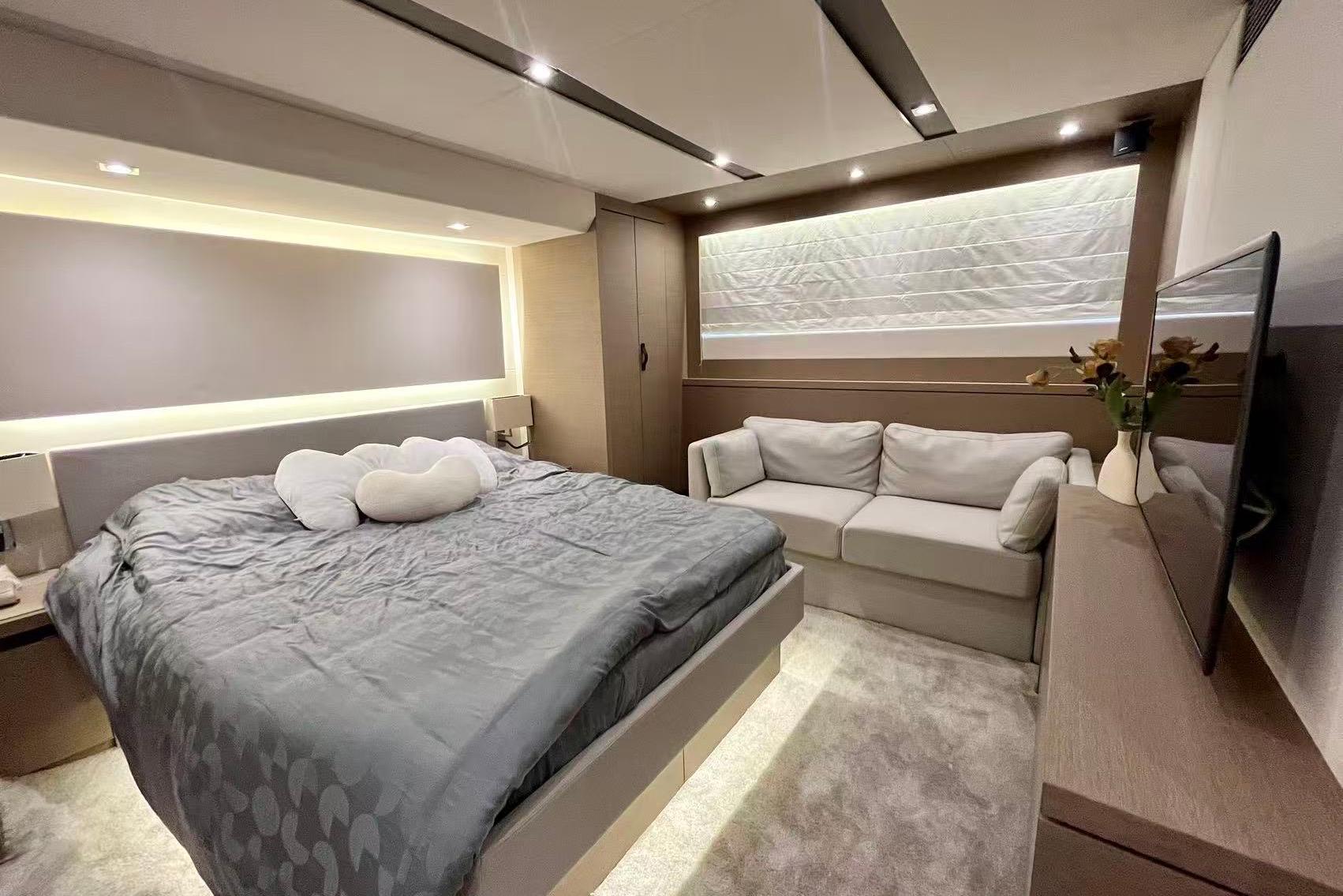 Luxurious bedroom interior on a 2019 Prestiage 630 yacht, featuring a cozy bed and sofa.