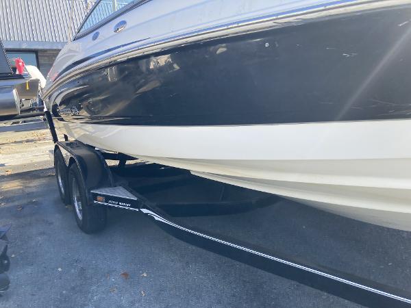 2008 Chaparral 210 SSi boat on trailer, black and white hull, parked outdoors.