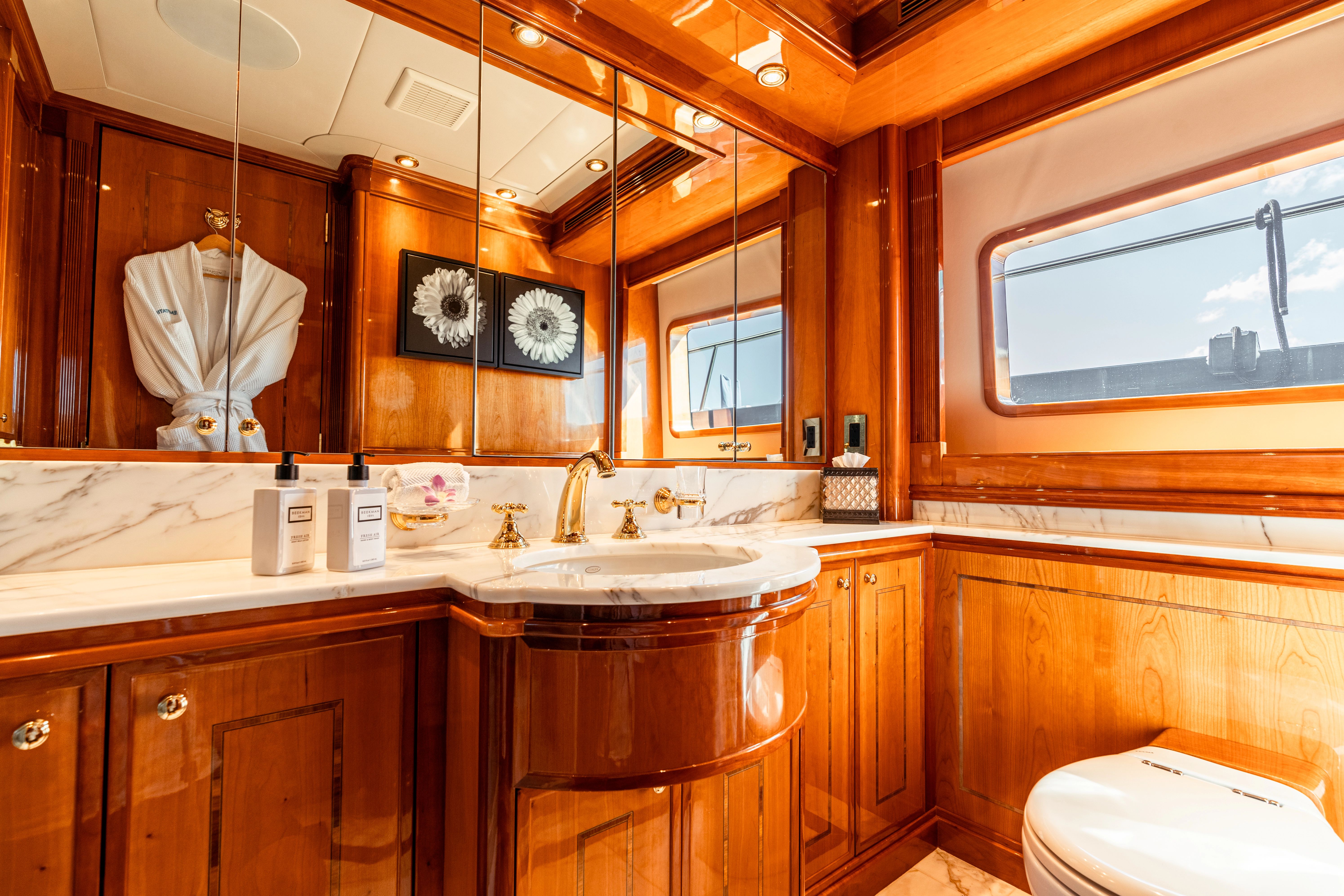Luxurious bathroom with wood paneling, marble surfaces, and gold fixtures on a yacht.
