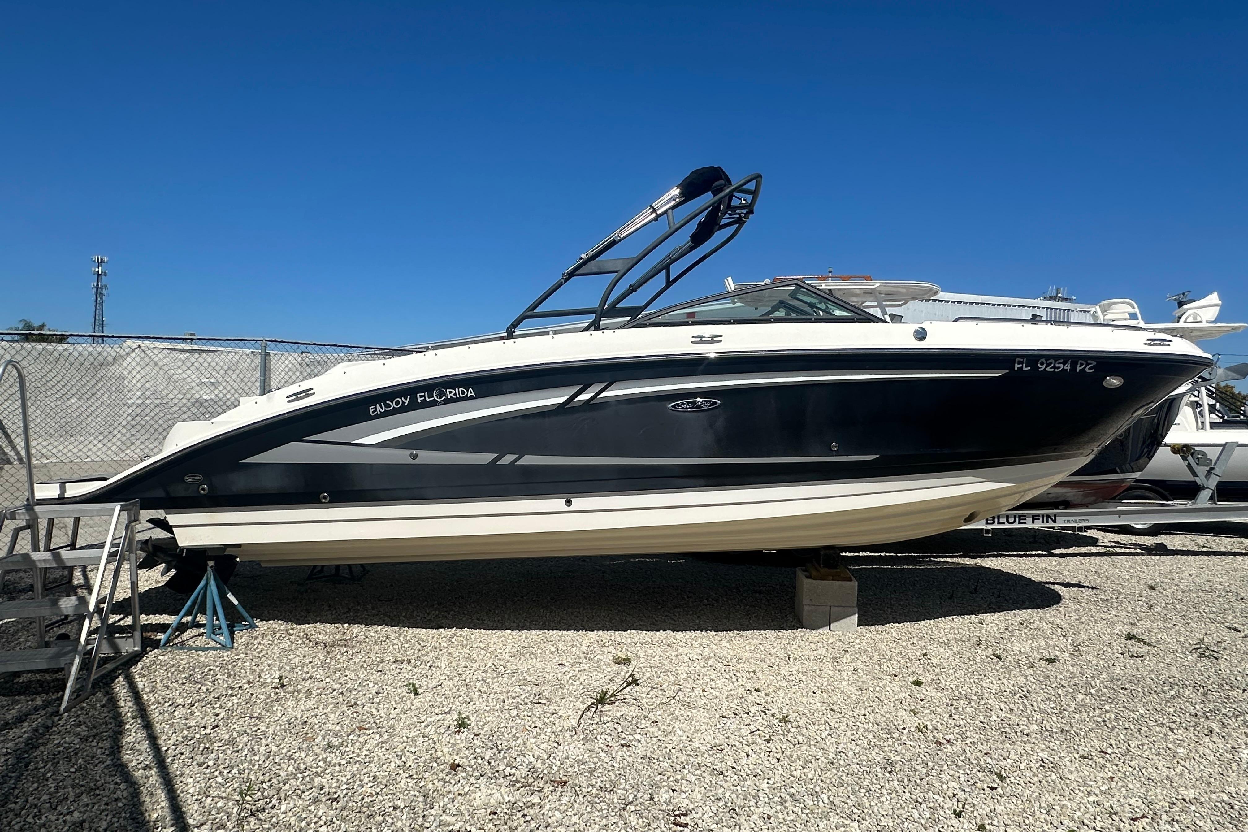 2016 Sea Ray 270 Sundeck boat on gravel lot under clear blue sky.