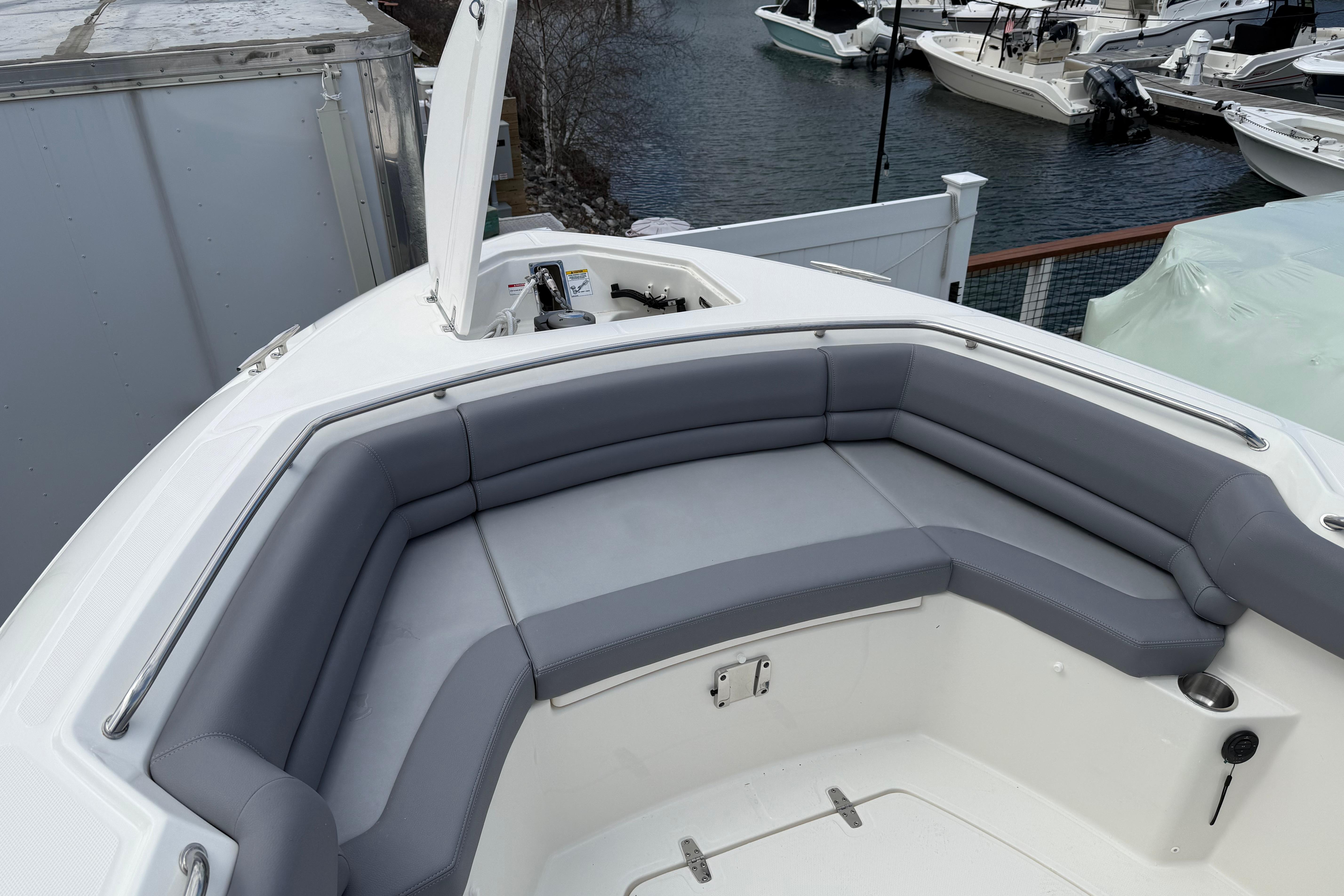 2026 Boston Whaler 330 Outrage boat with gray cushioned seating at marina.