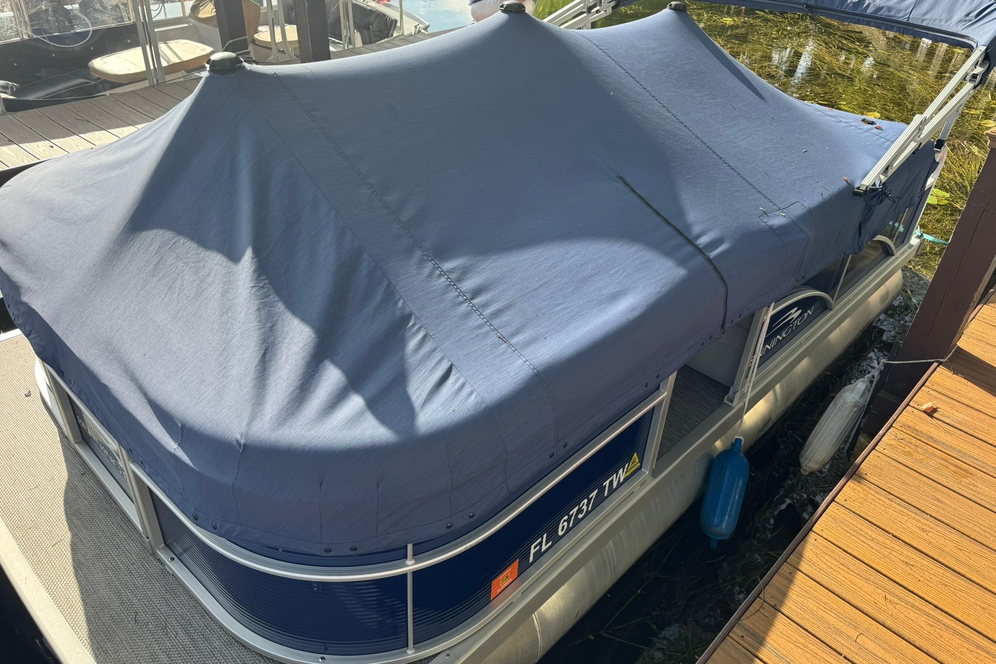 2024 Bennington SV 168 SLV pontoon boat with blue cover docked at marina.