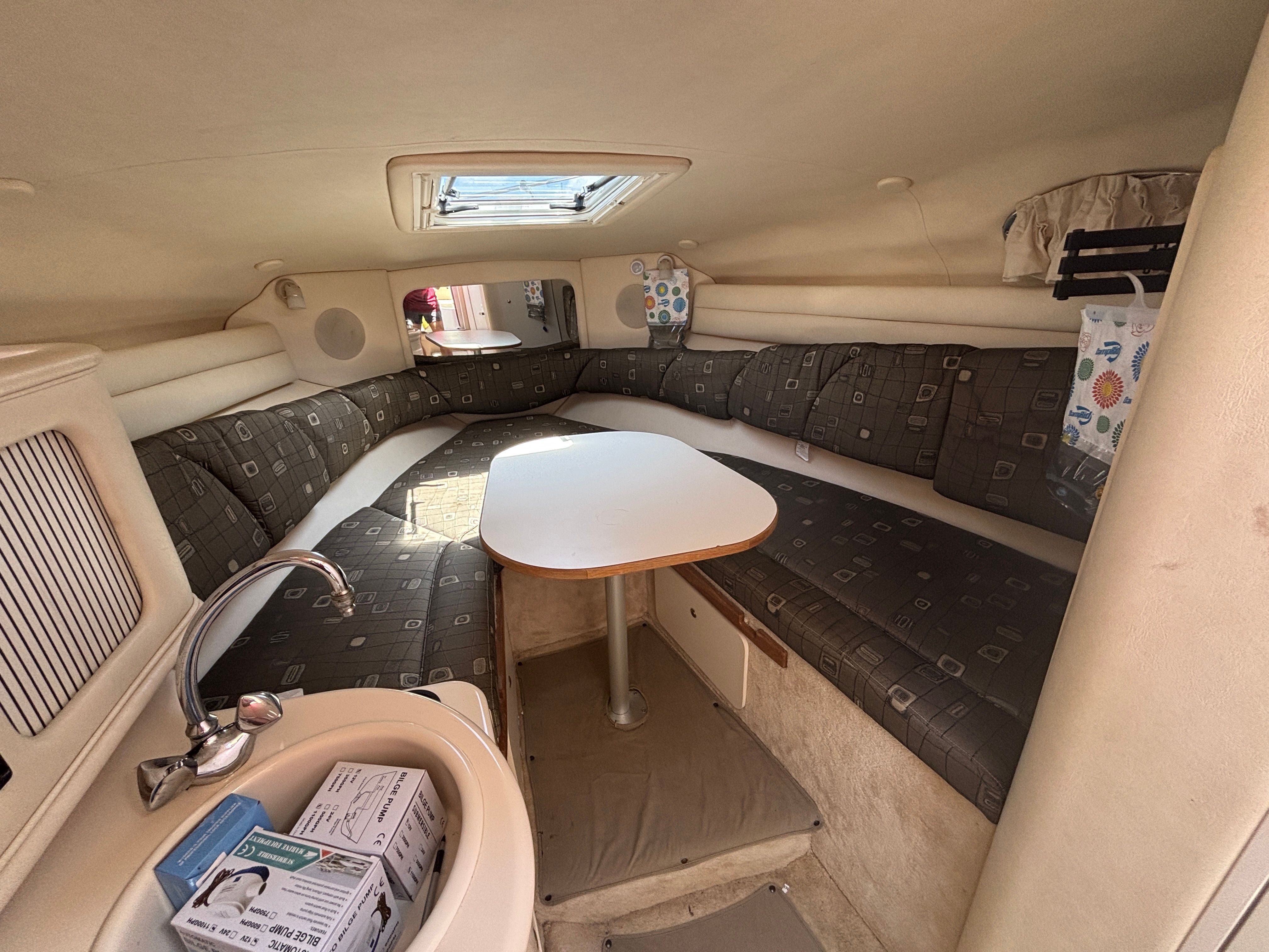 Interior of a 2000 Sea Ray Sundancer 260 with cushioned seating and a table.