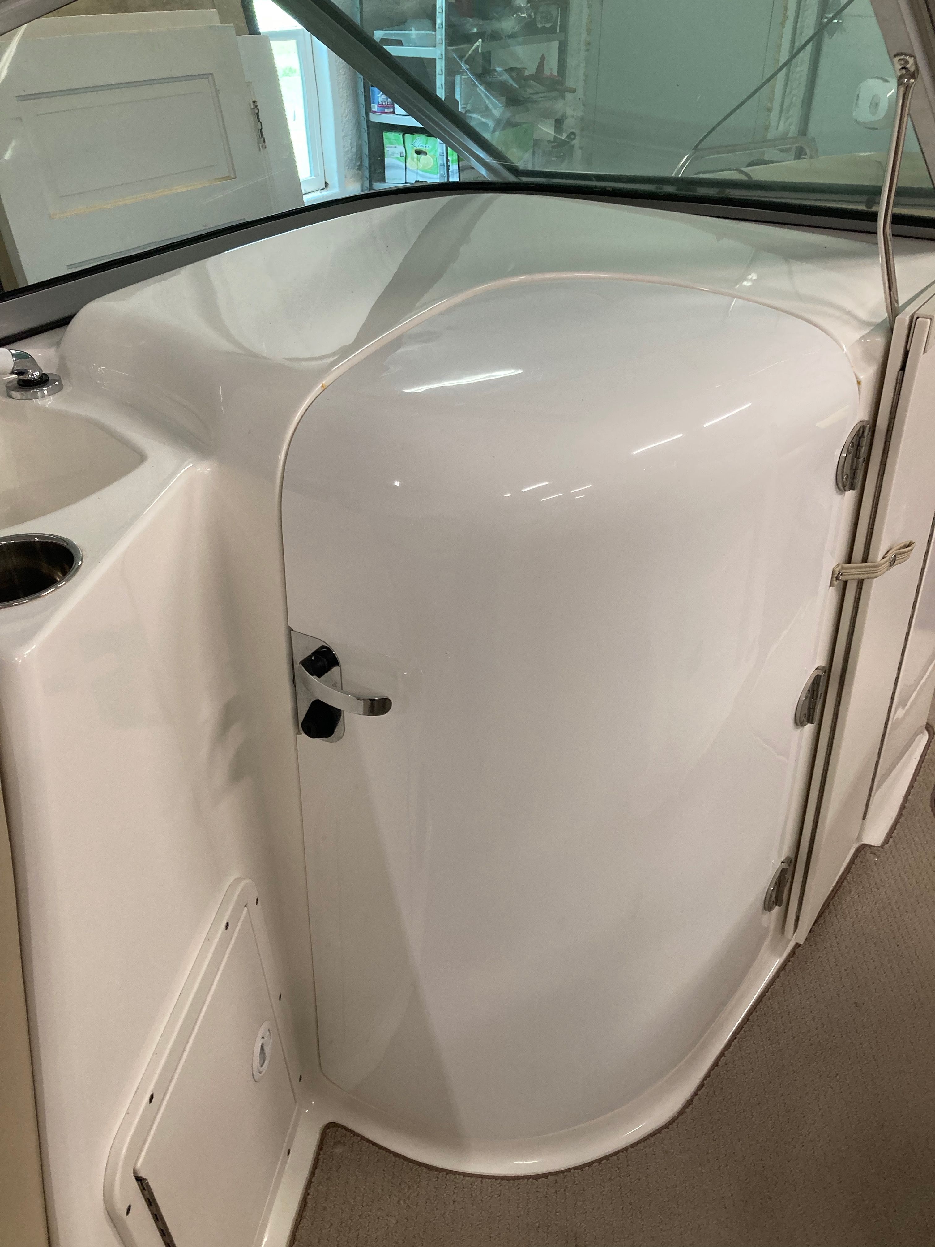 Interior view of a boat with a white, glossy enclosure and door.