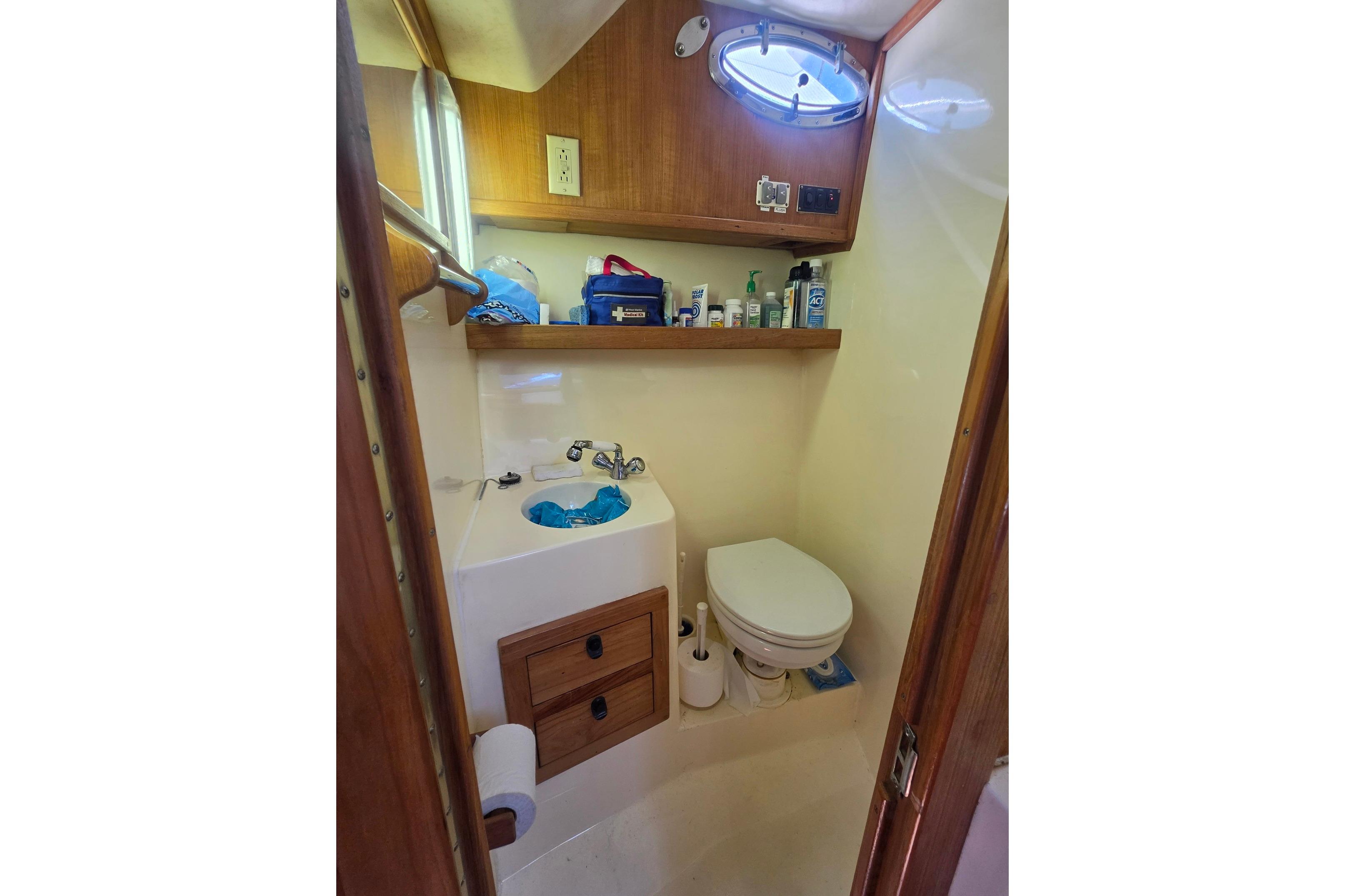 Compact bathroom in a 1999 Albemarle 305 Express Fisherman boat with sink and toilet.