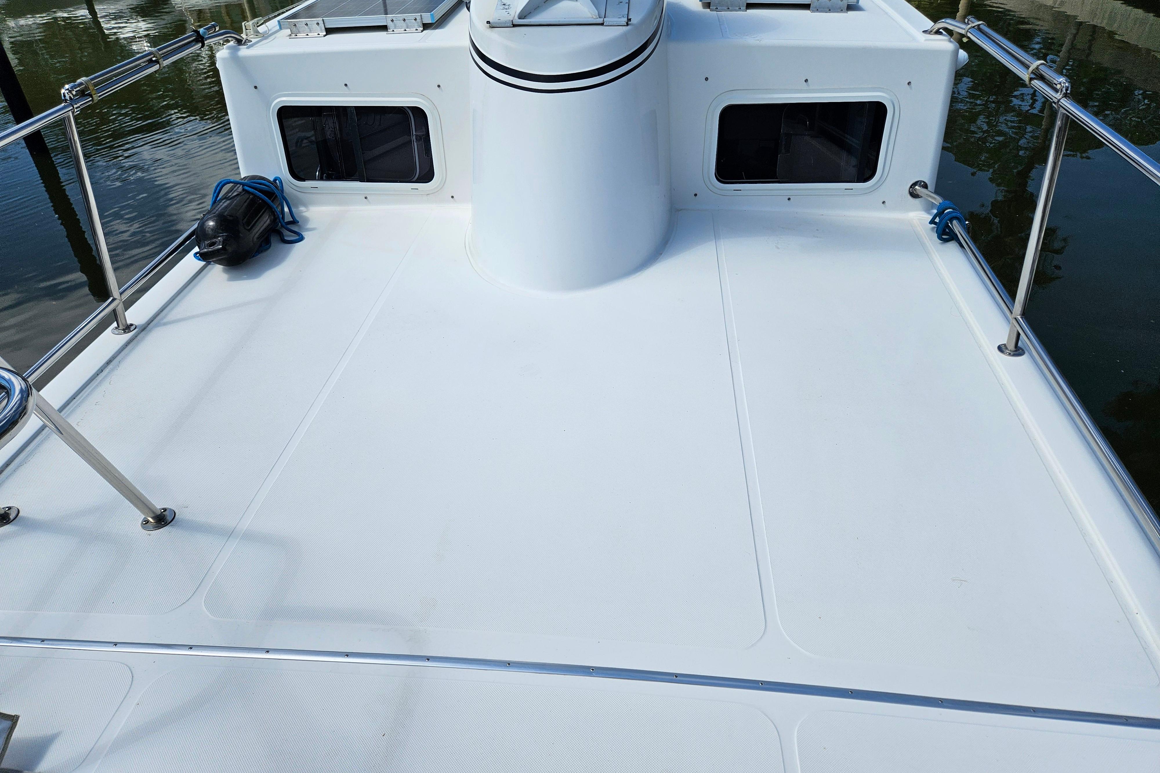 2006 American Tug AT boat deck with railing and windows, docked on calm water.