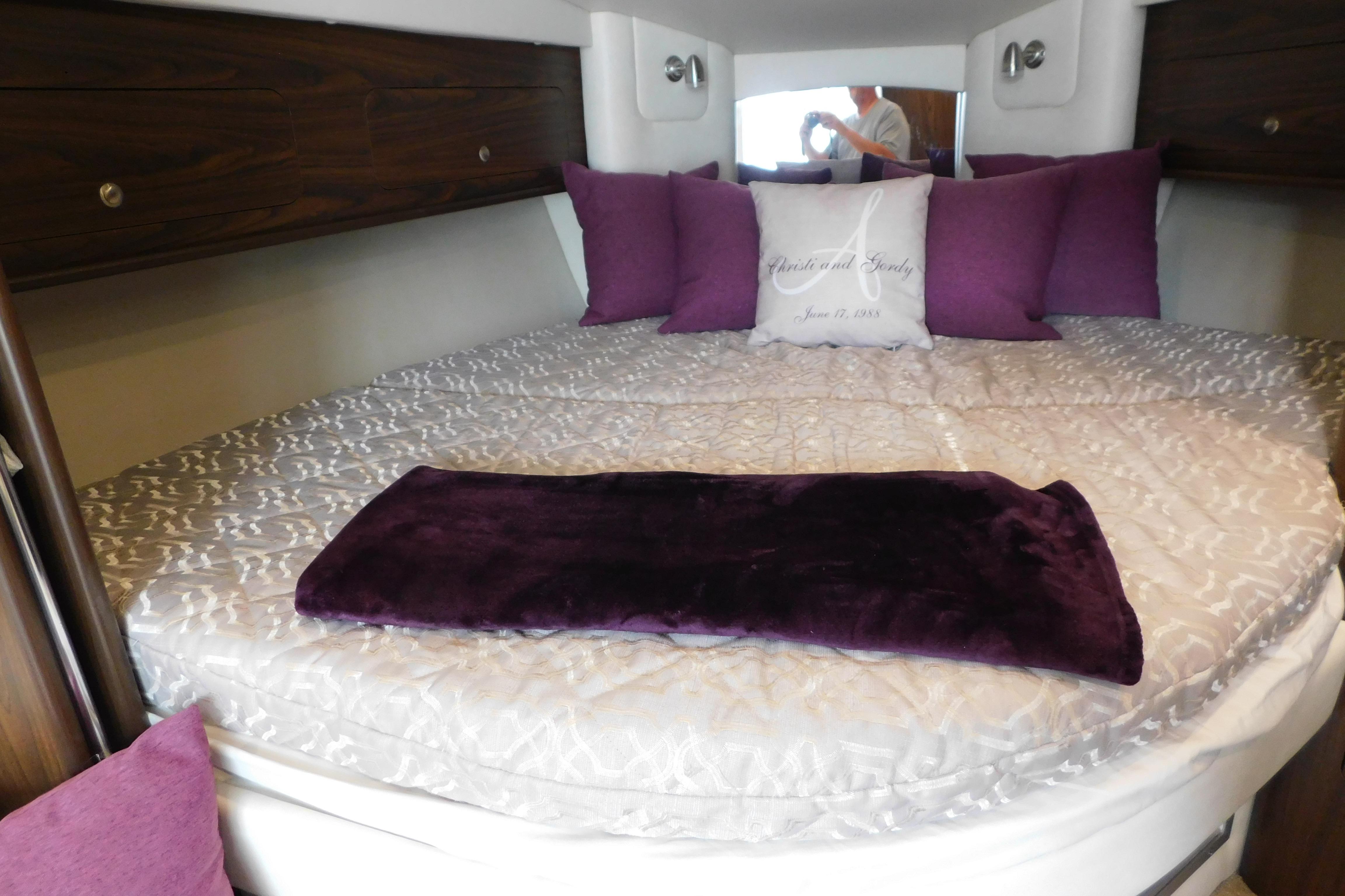 Cozy cabin interior of 2017 Rinker EX 320 with plush bedding and purple accents.