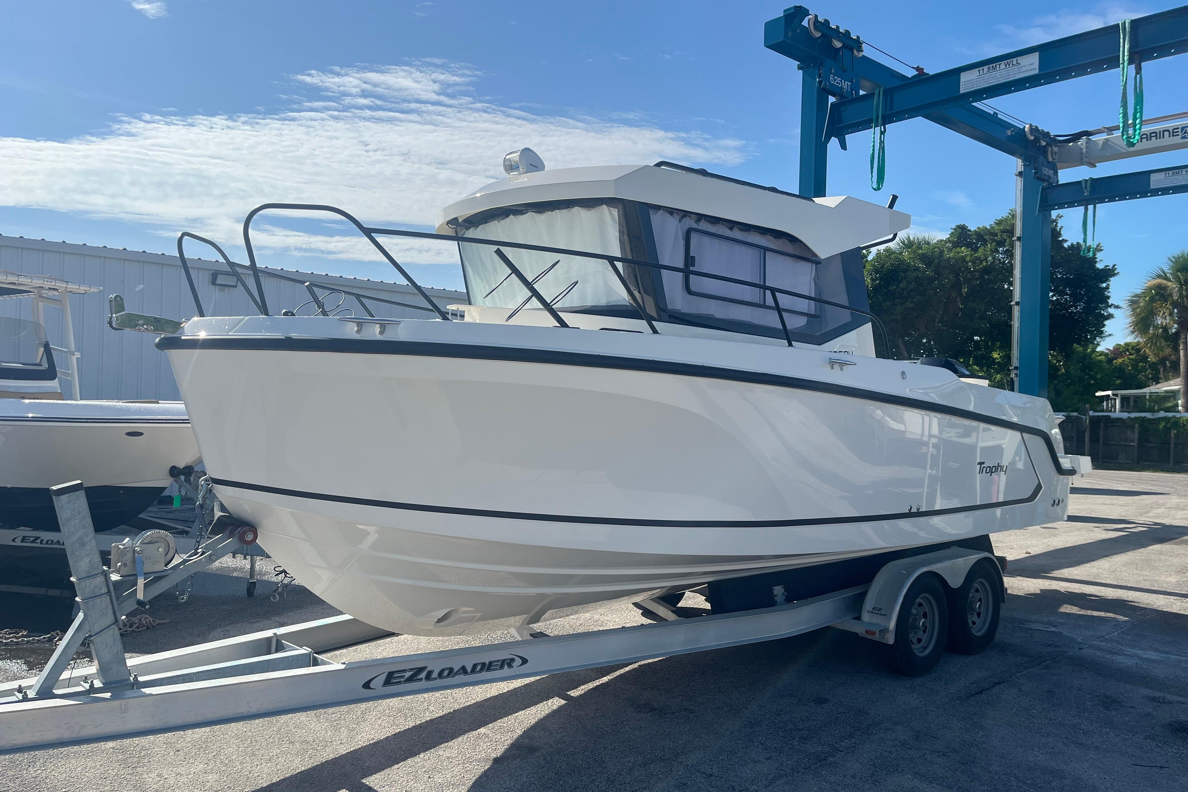 2025 Bayliner Trophy T25 Pilothouse boat on trailer under clear sky.