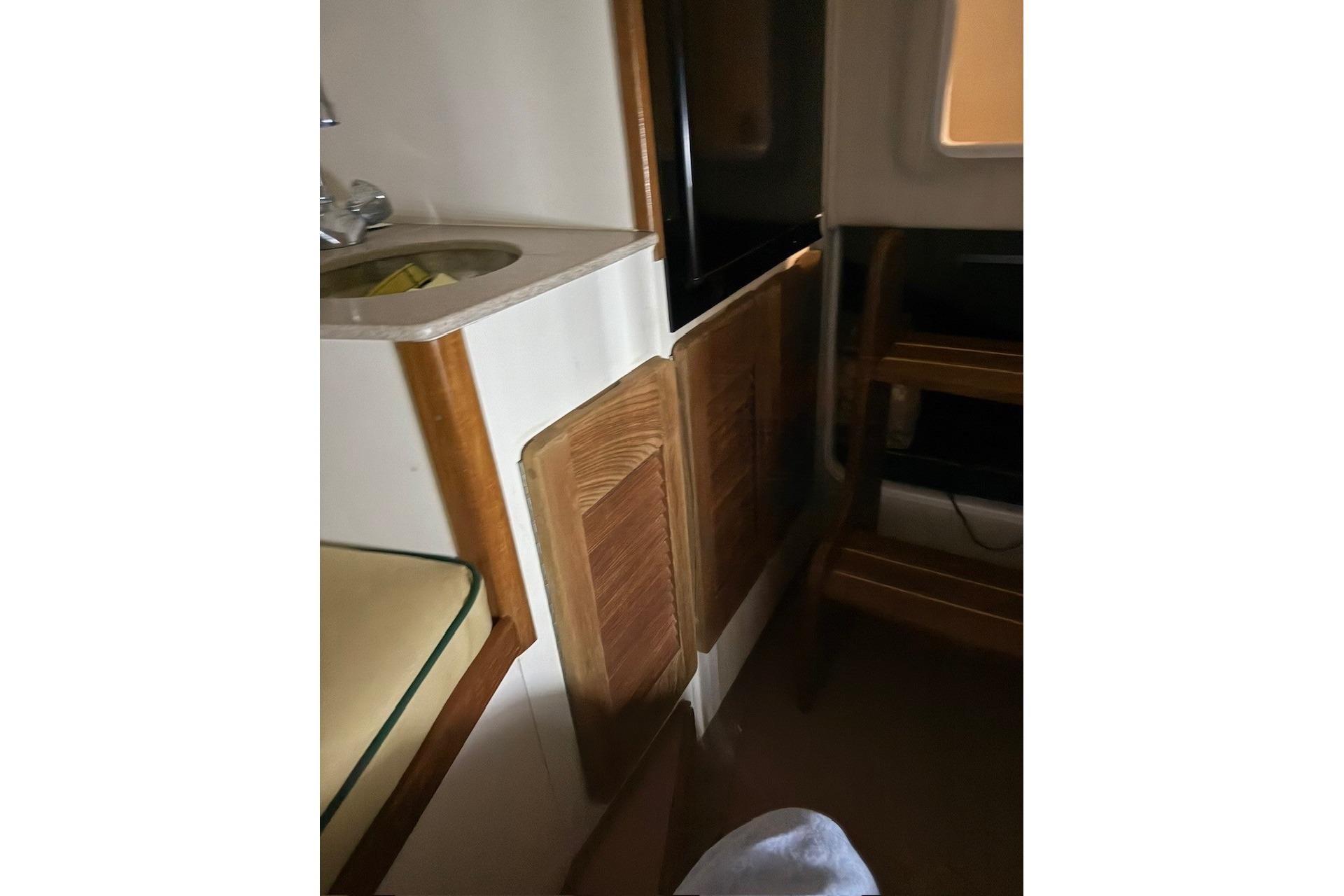 Interior of 2000 Pursuit 3070 Offshore Center Console with sink and wooden cabinetry.