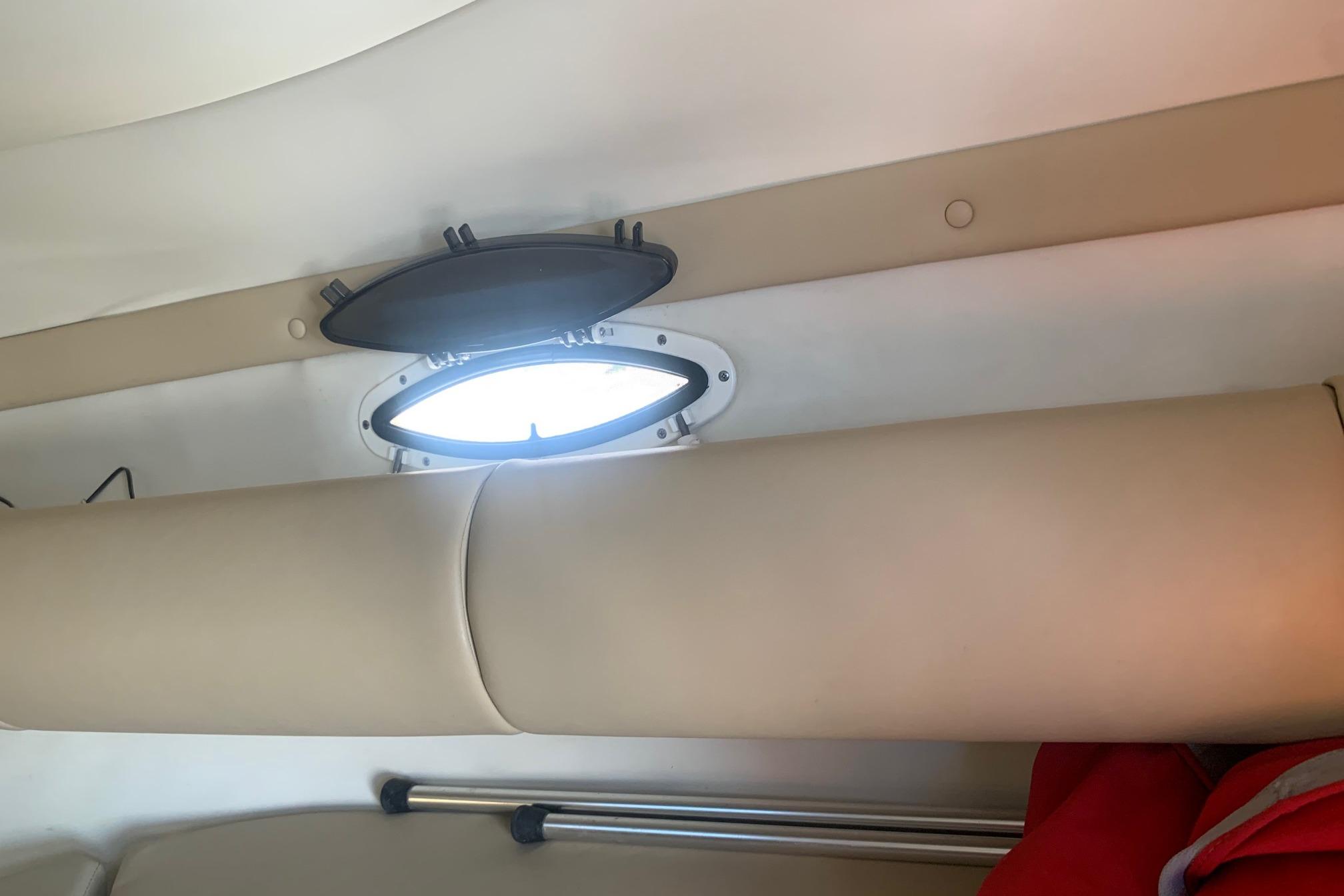 Interior of 2006 Rinker 282 Captiva Cuddy with open porthole and beige upholstery.