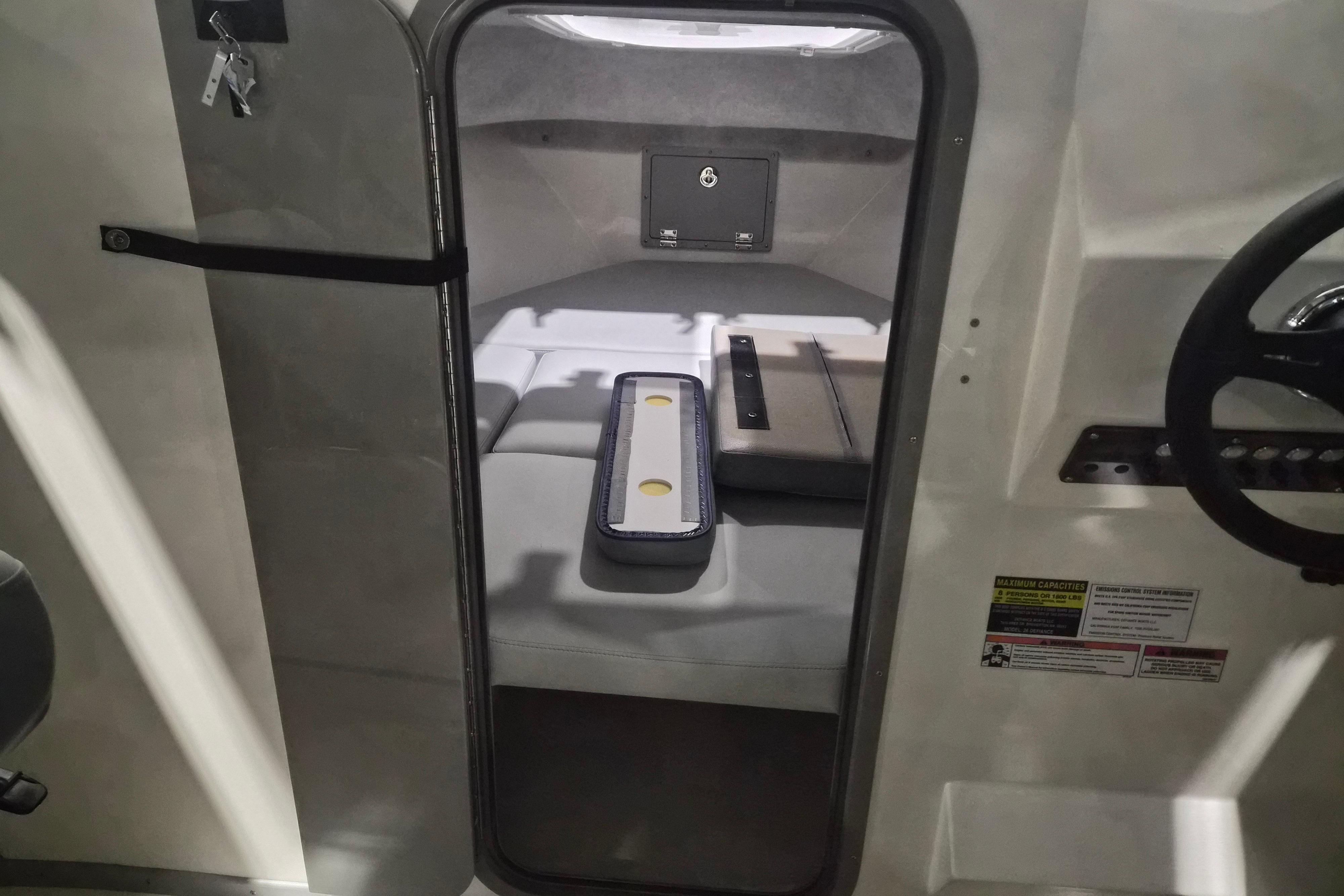 Interior cabin view of 2026 Defiance Admiral 260 EX boat, featuring seating and control panel.