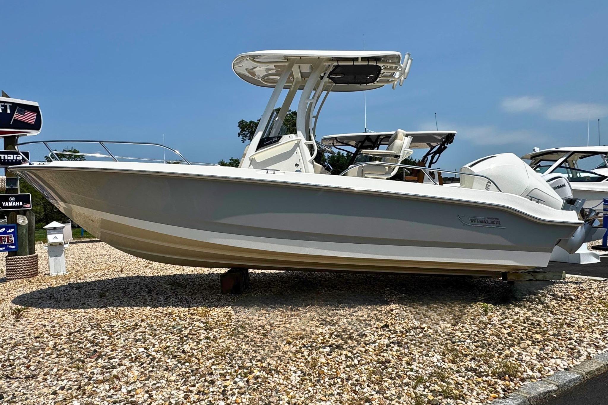 2026 Boston Whaler 220 Dauntless boat displayed on gravel lot under clear sky.
