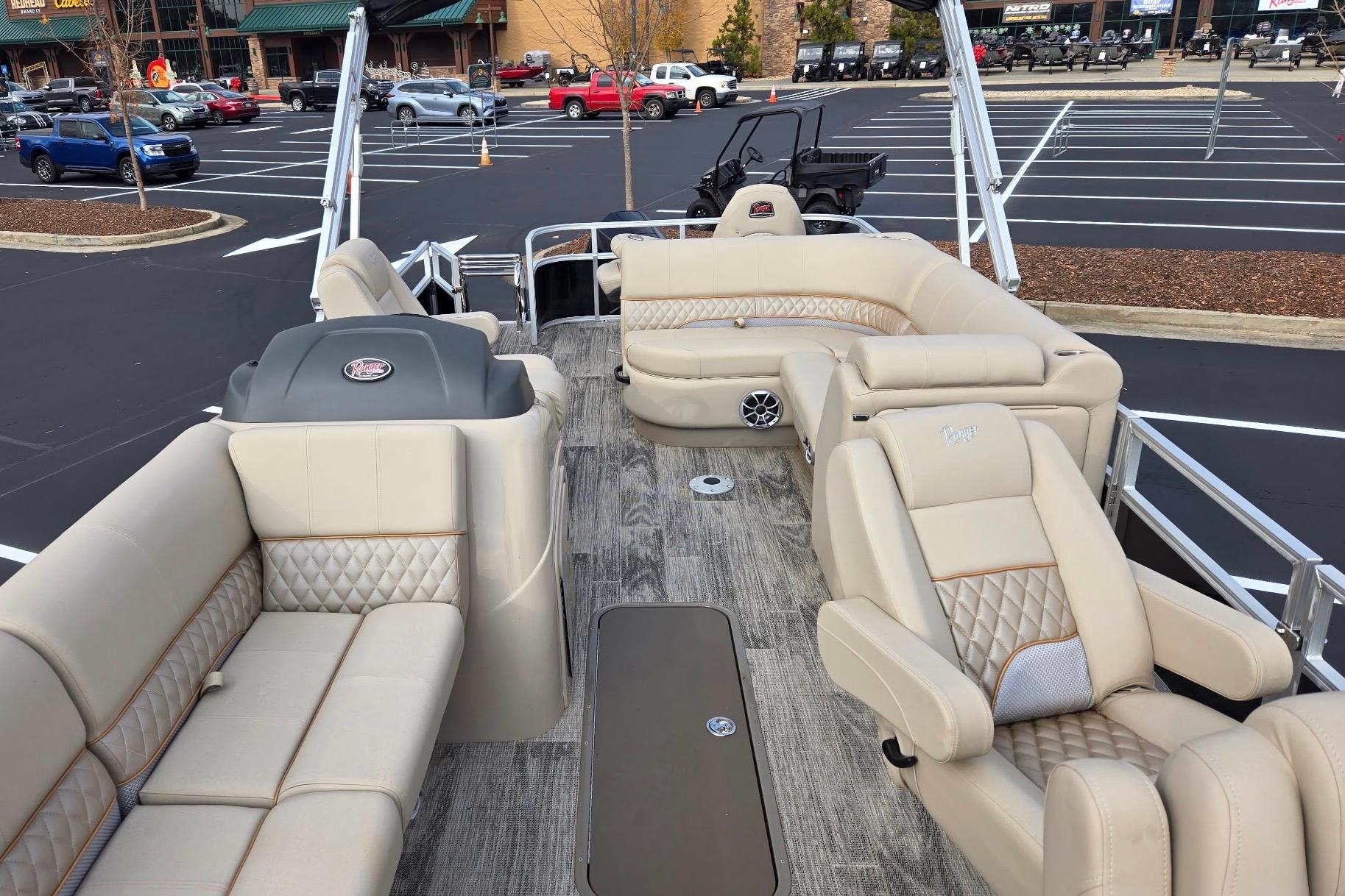 2025 Ranger Reata 223FC pontoon boat with luxurious beige seating in a parking lot.