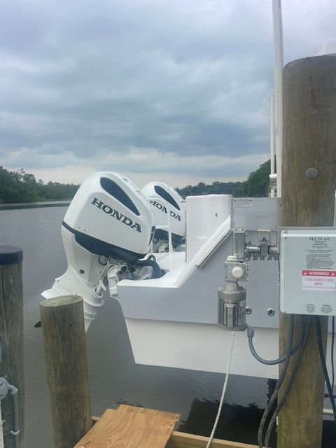 Two Honda outboard motors on a boat at the dock, with a cloudy sky in the background.
