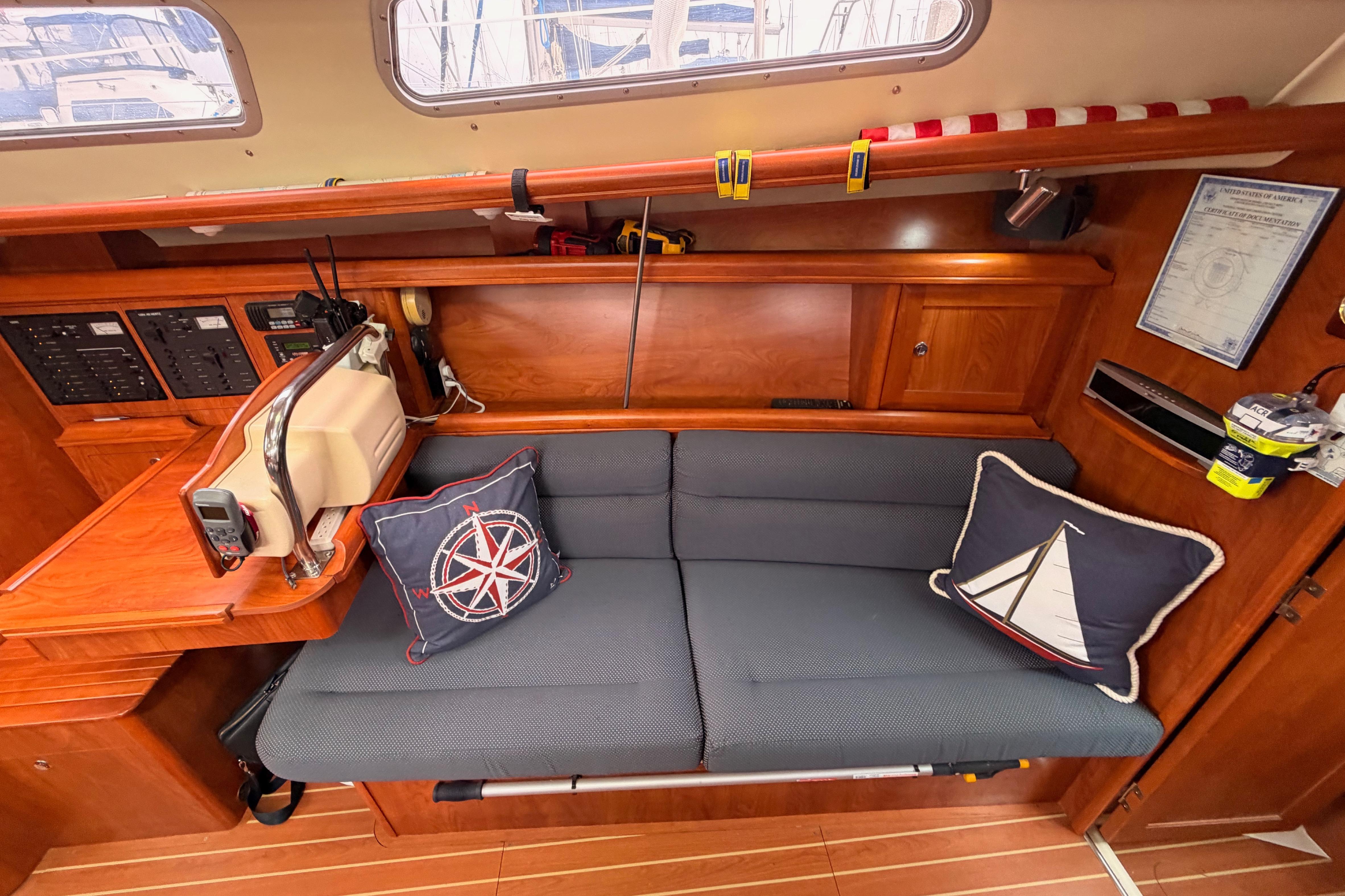 Cozy interior of 2009 Hunter 38 sailboat with nautical-themed cushions and wooden cabinetry.