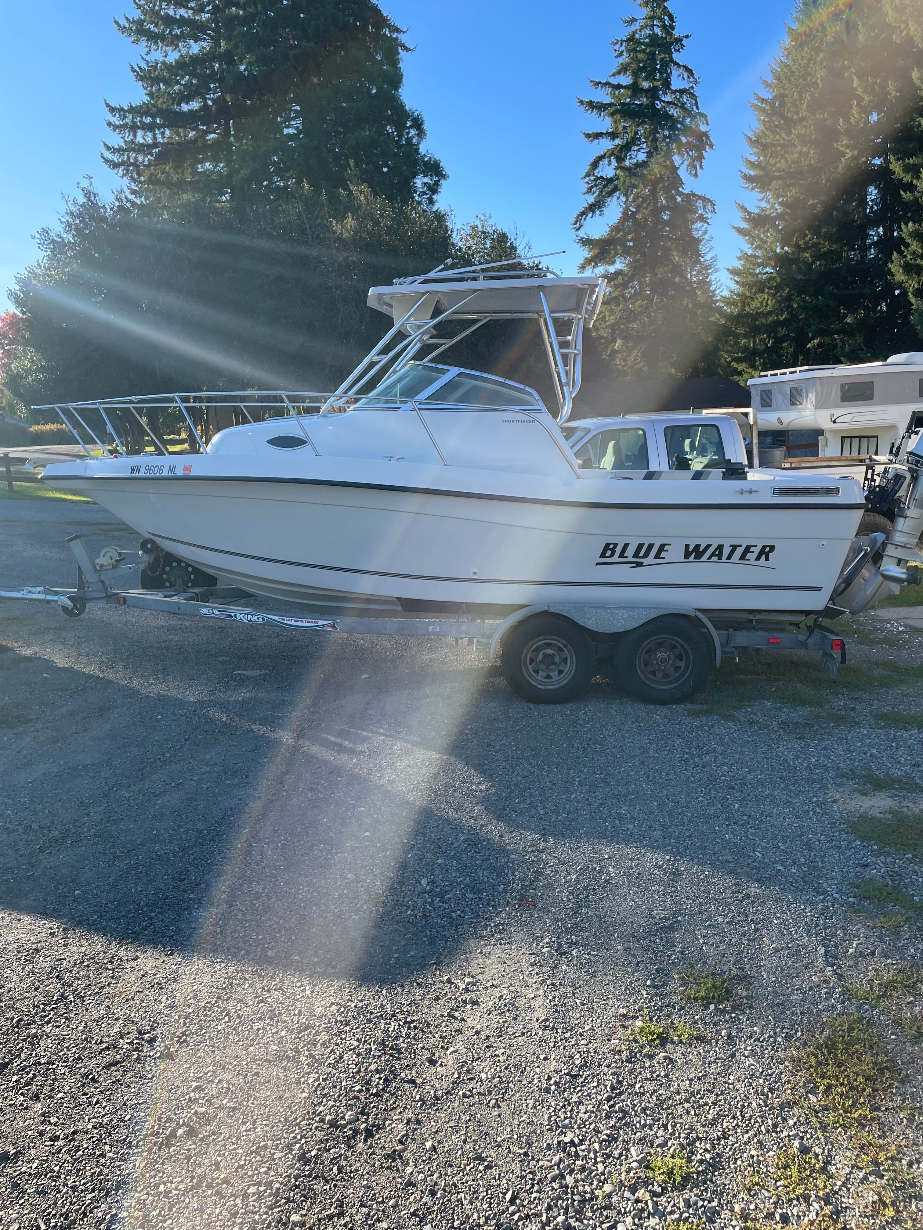 A 2001 Bluewater 2100 Sport Fisher on a trailer, surrounded by trees and RVs.
