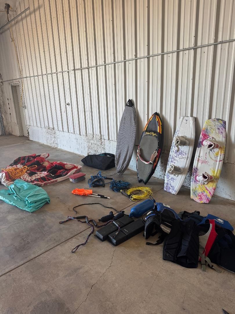 Watersports gear on the ground, including wakeboards, ropes, and life jackets.