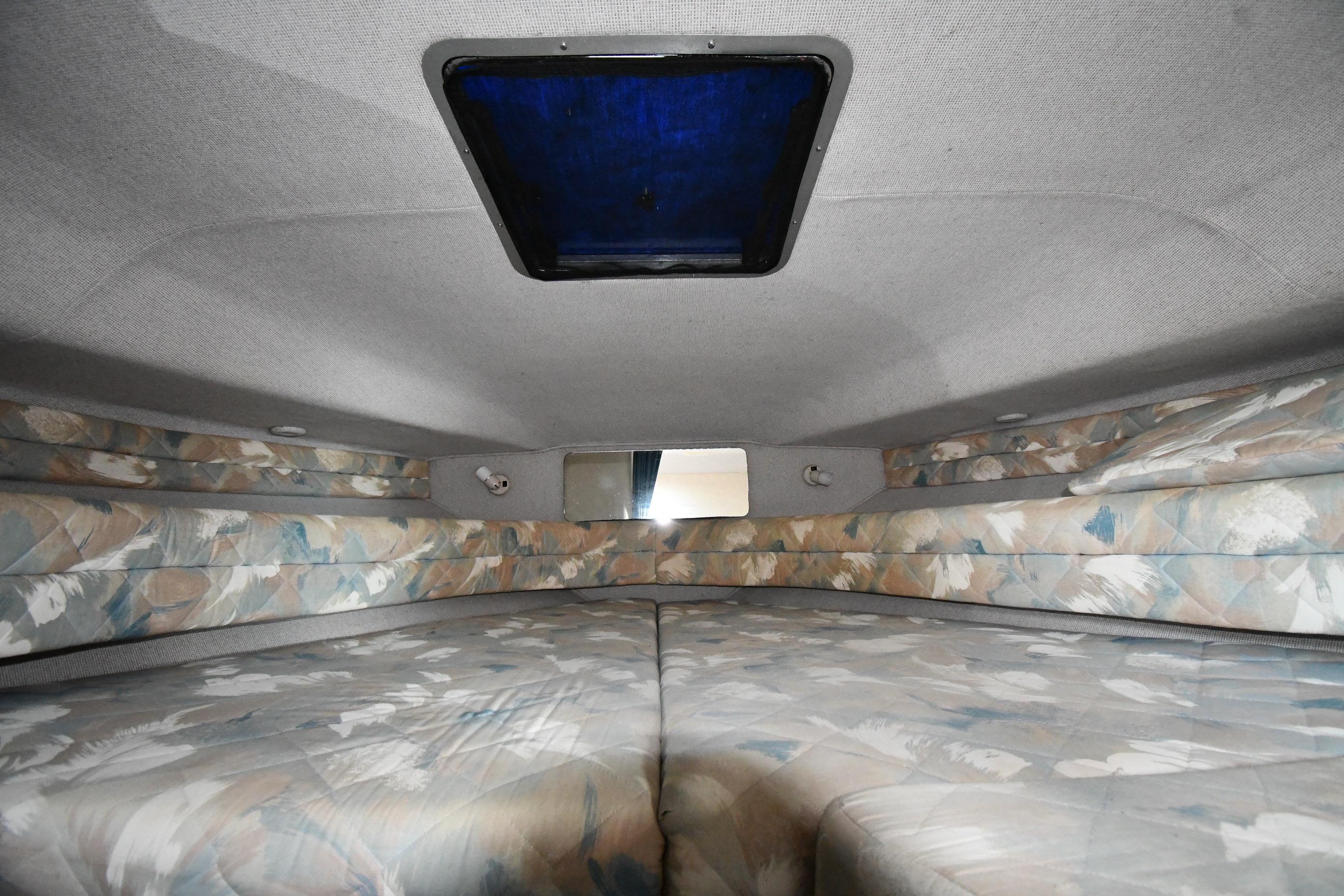 Interior cabin of 1993 Sea Ray 300 Sundancer with patterned upholstery and overhead hatch.
