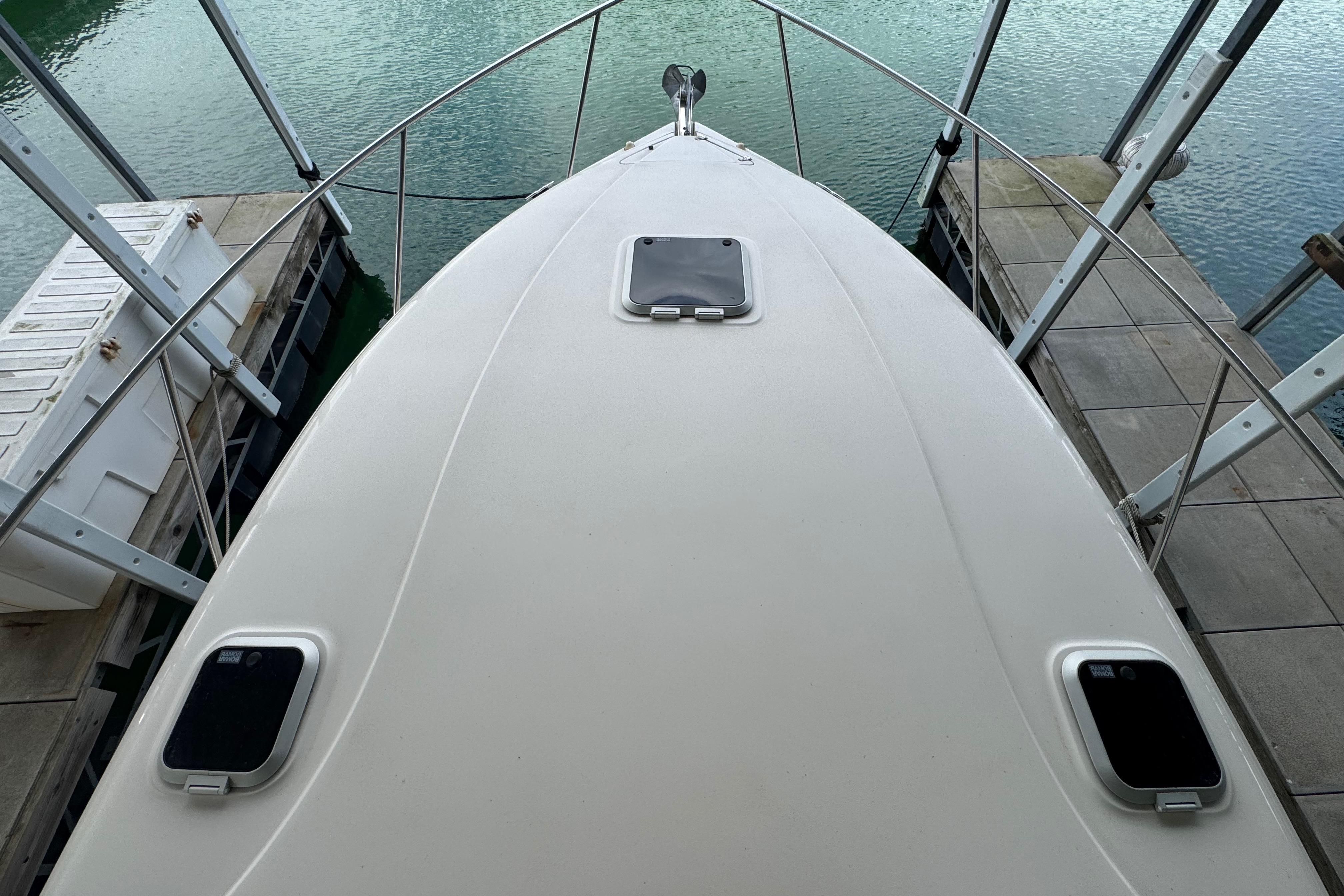 2004 Rinker Fiesta Vee 312 boat deck at dock, surrounded by calm water.