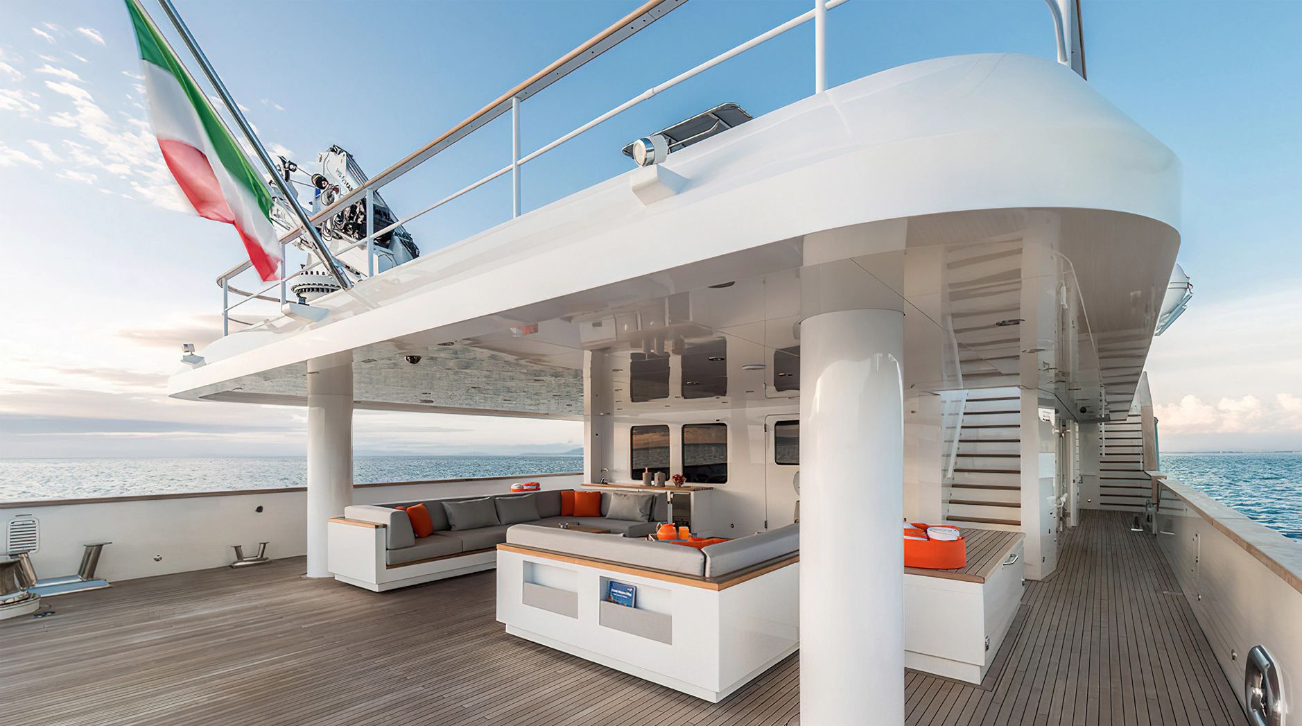 The image shows the deck of a luxury yacht with a seating area and ocean view.
