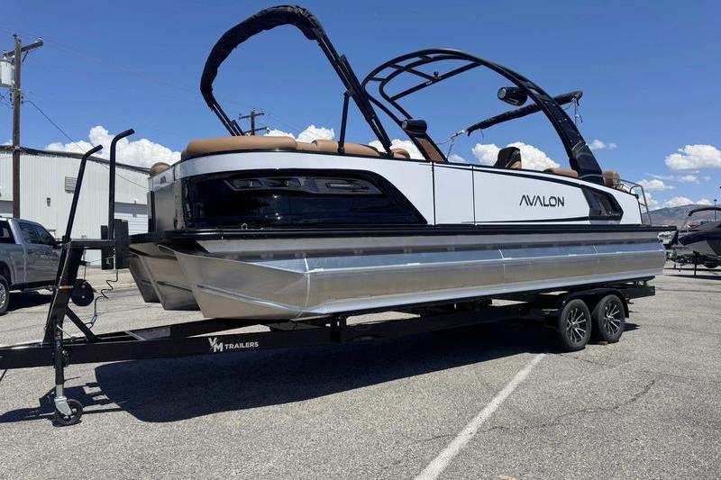 2026 Avalon Excalibur LTD Quad Lounge pontoon boat on trailer, parked outdoors.