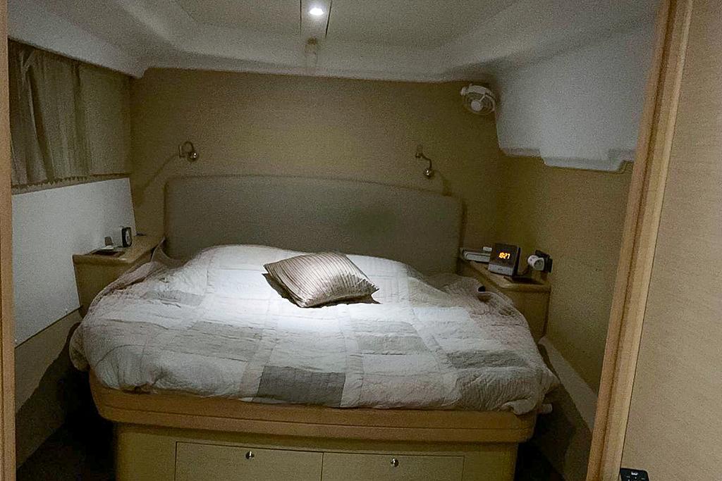 Cozy bedroom interior of 2009 Lagoon 440 yacht with double bed and ambient lighting.