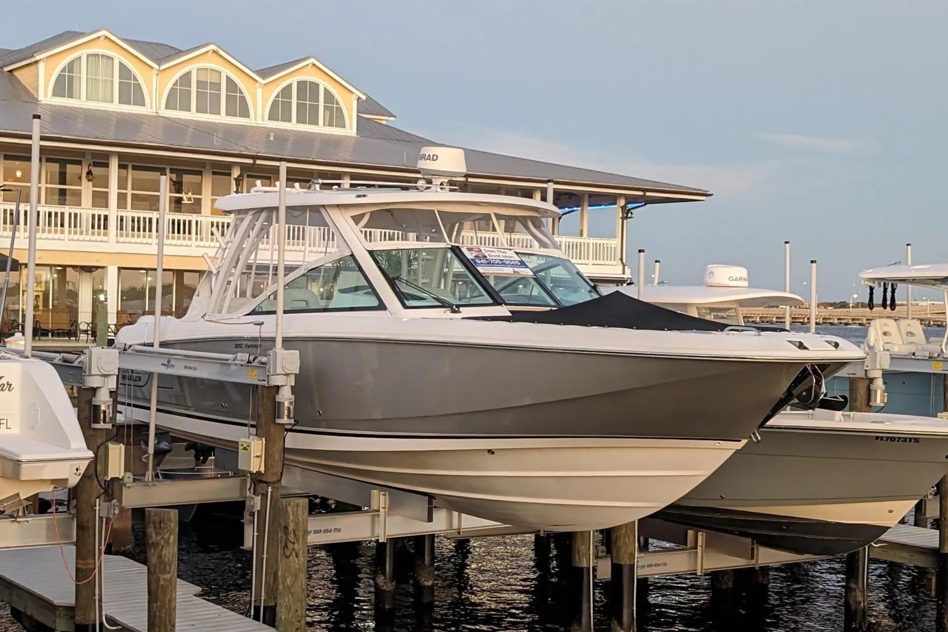 2017 Boston Whaler 320 Vantage docked at marina with waterfront building backdrop.