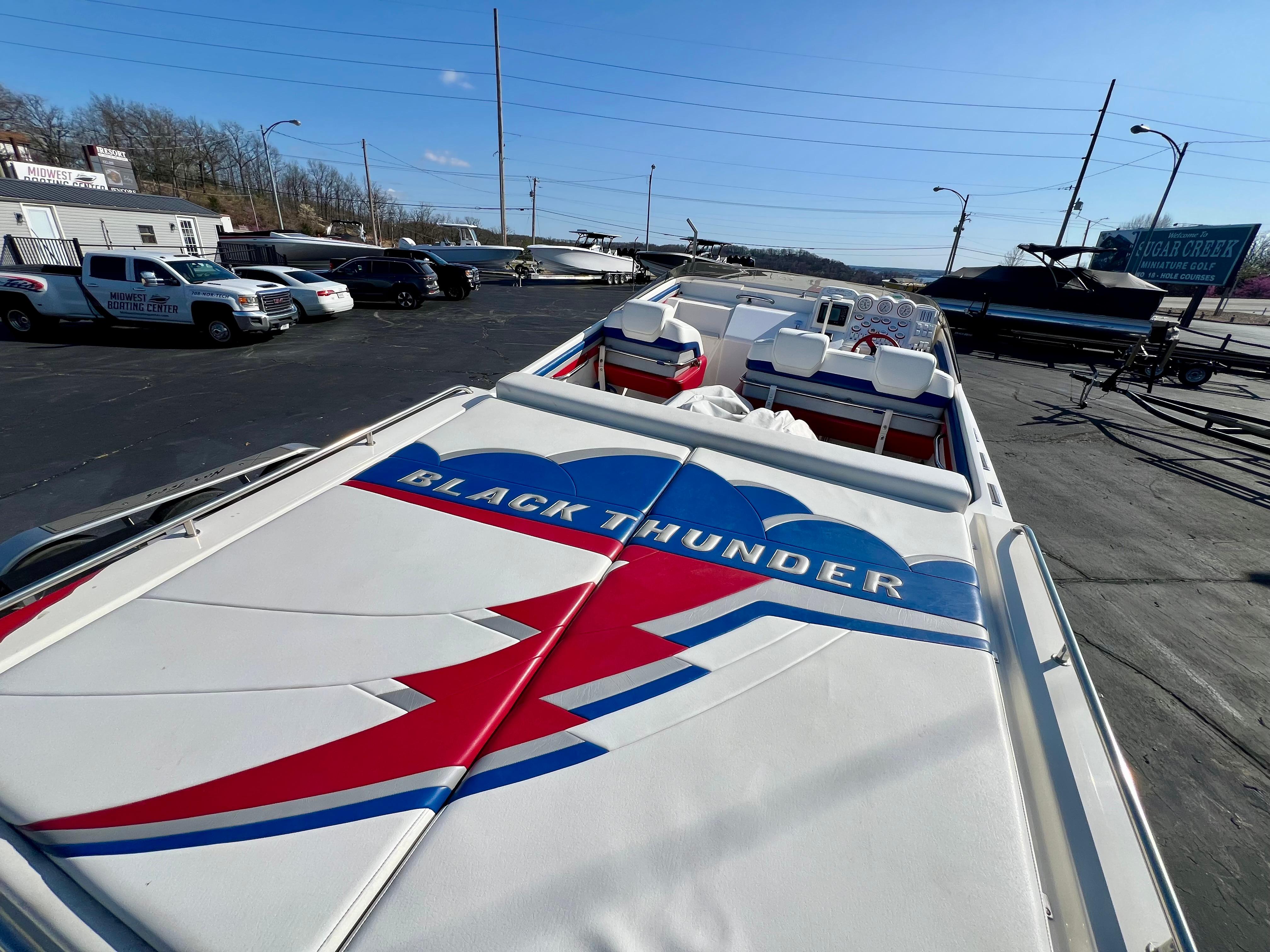 1999 Black Thunder 430 Flat Deck boat with vibrant graphics, parked outdoors.