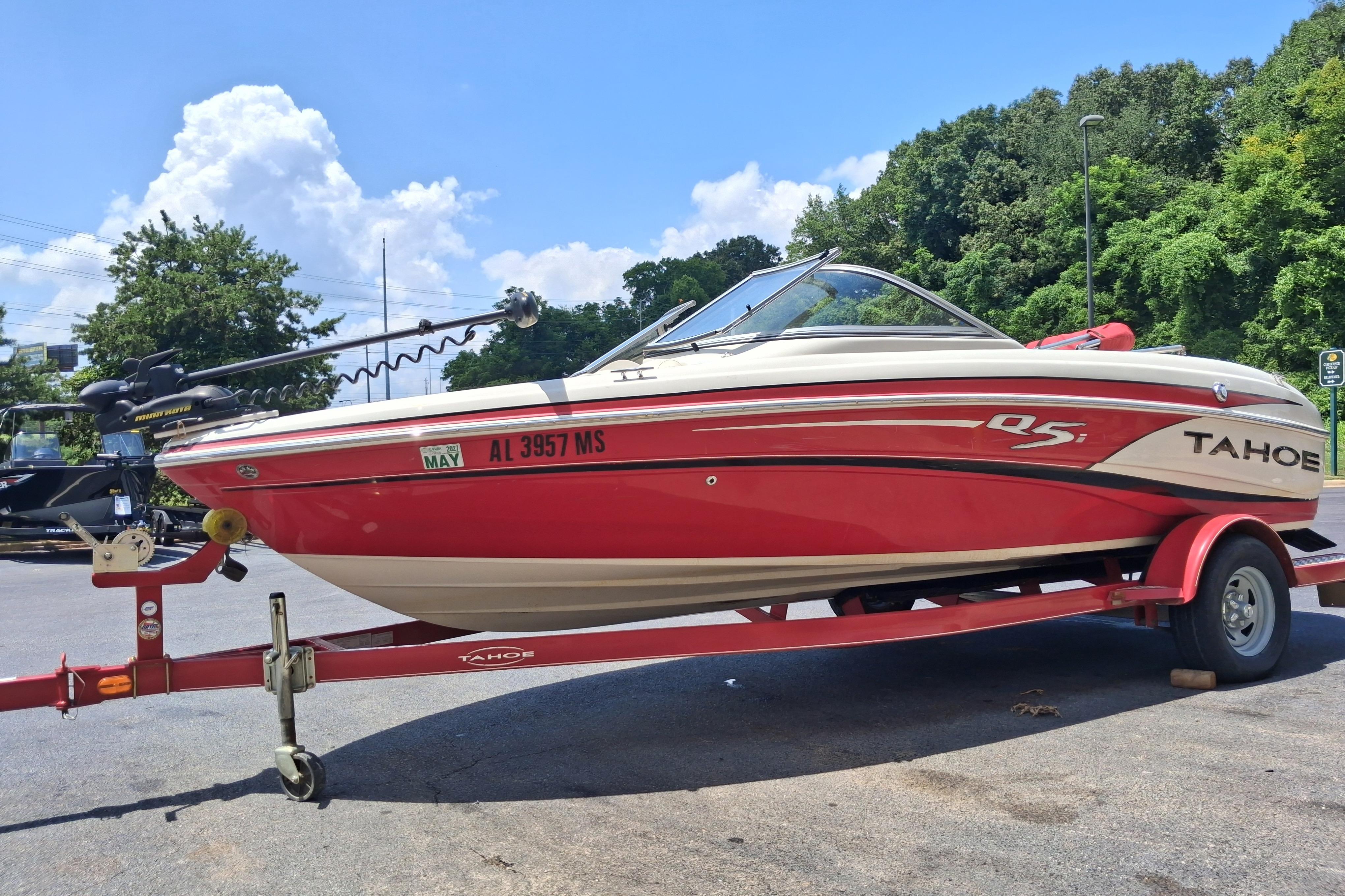 Red 2014 Tahoe Q5i boat on trailer, parked outdoors under a clear blue sky.