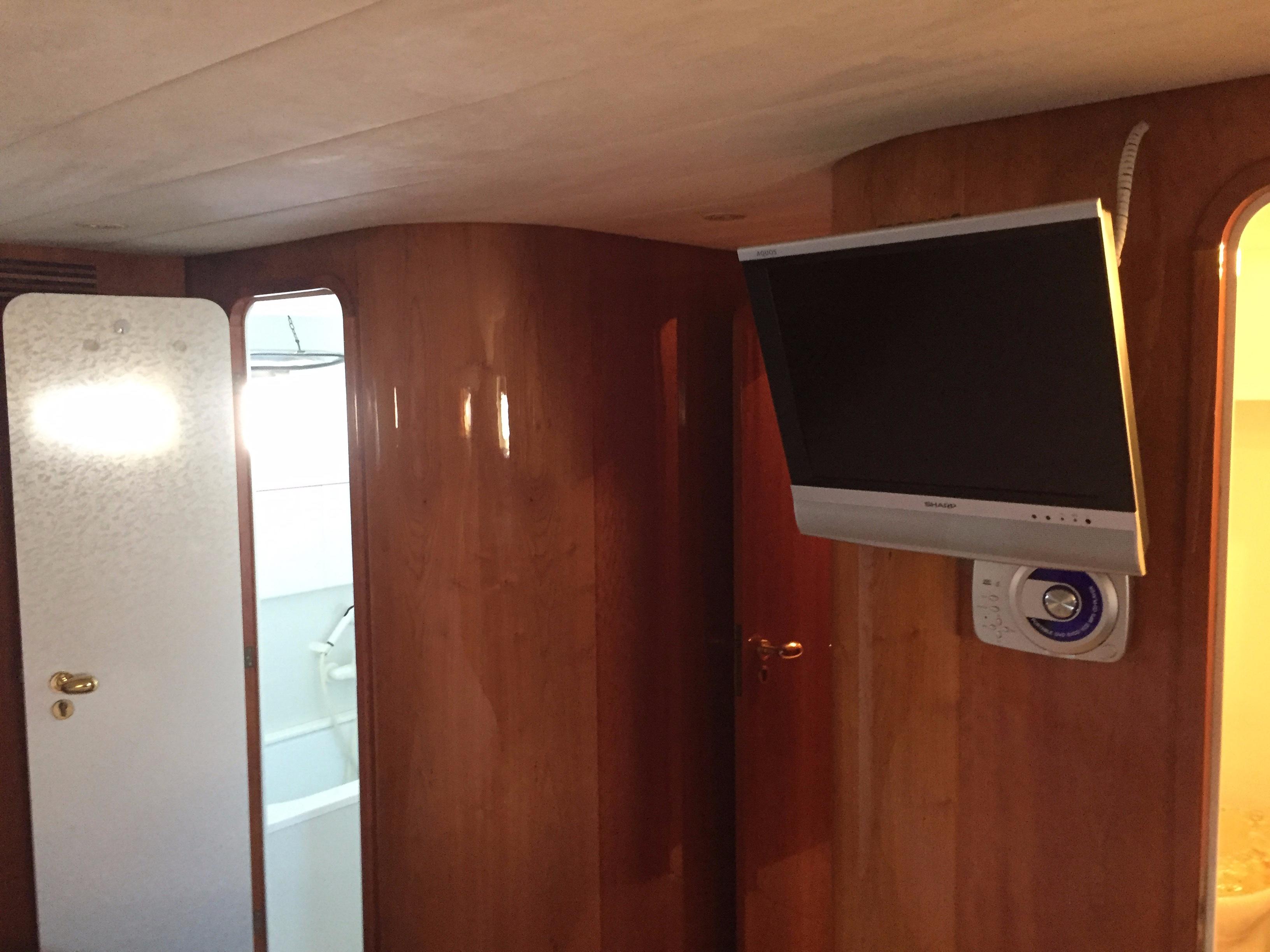 Interior of 1994 Falcon 76 yacht with mounted TV and wooden paneling.